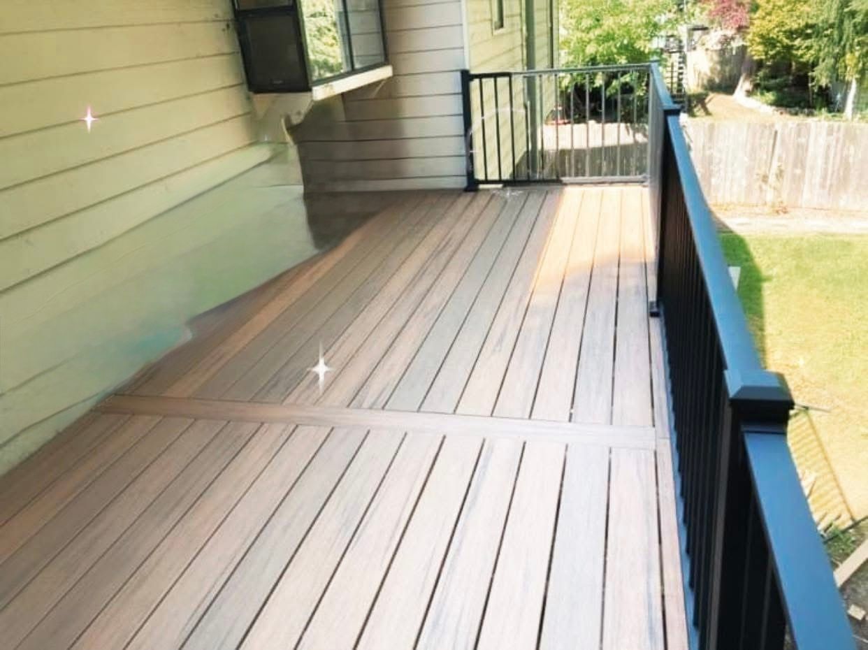 A wooden deck with black railings and a gate, attached to a light-colored house.