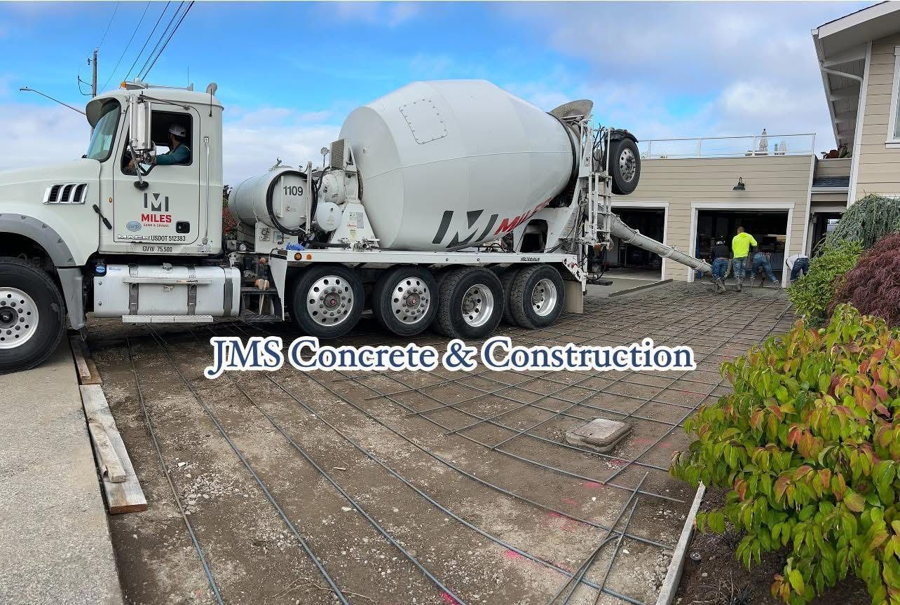 Concrete truck pouring concrete into a driveway form at a construction site.