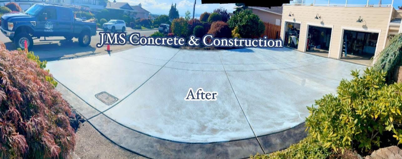 Newly poured concrete driveway. Shows a pickup truck, garage doors and greenery.