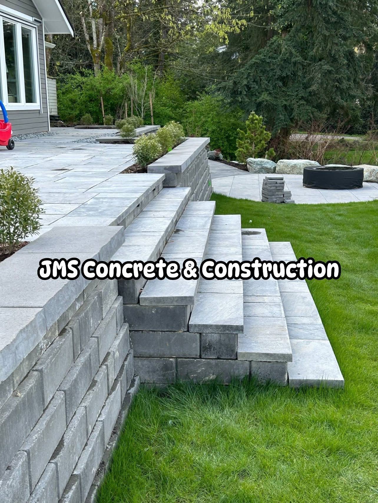 Concrete block retaining wall with steps built on a grassy lawn.