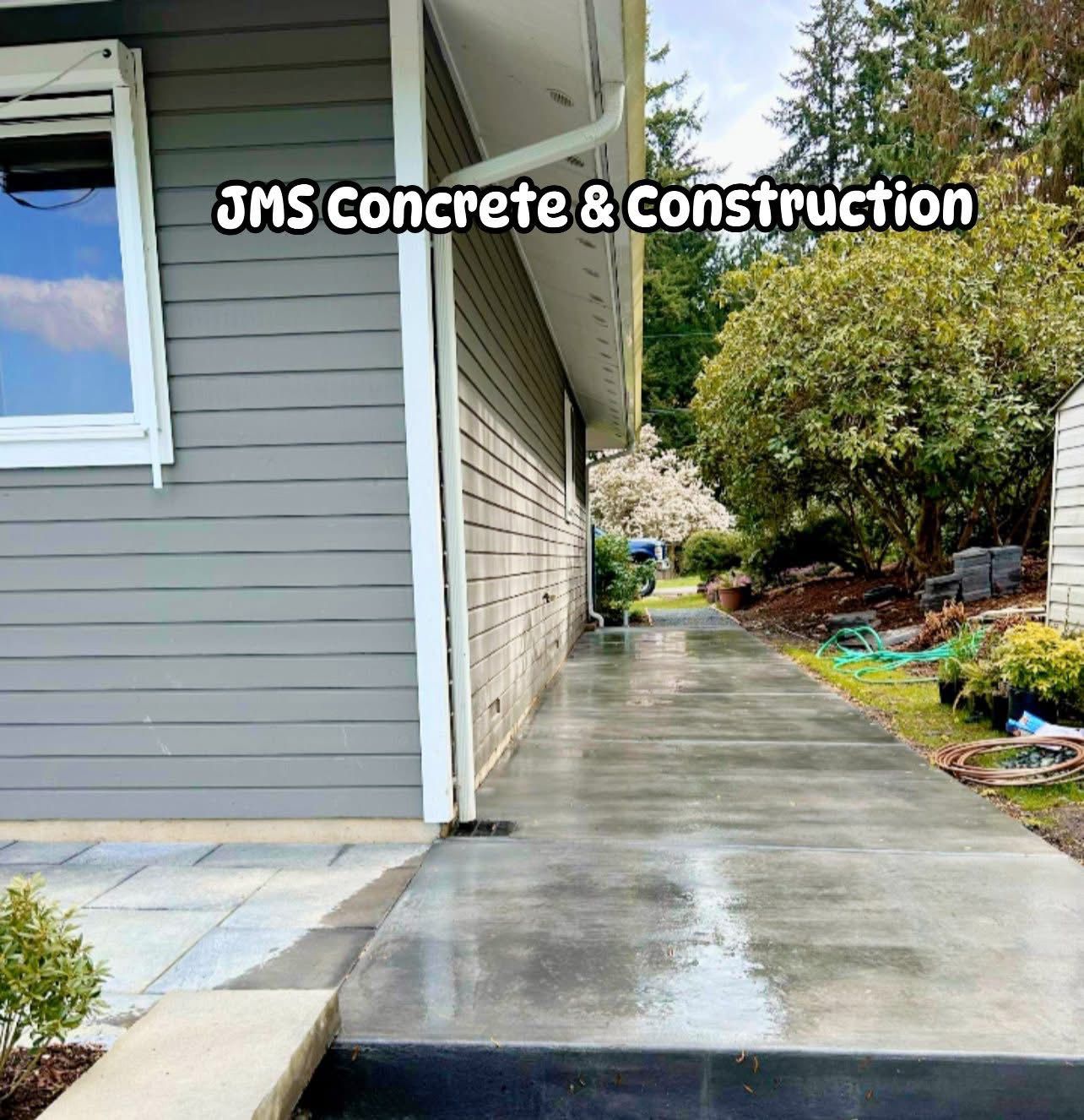 Gray concrete walkway next to a gray house, with landscaping and the business name
