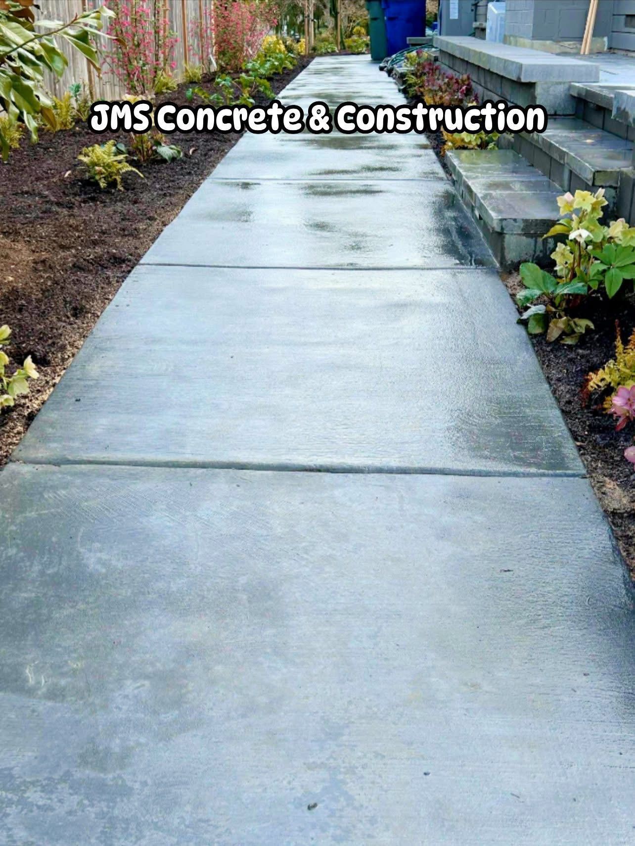 Concrete walkway with JMS Concrete & Construction logo, plants on either side, stairs.