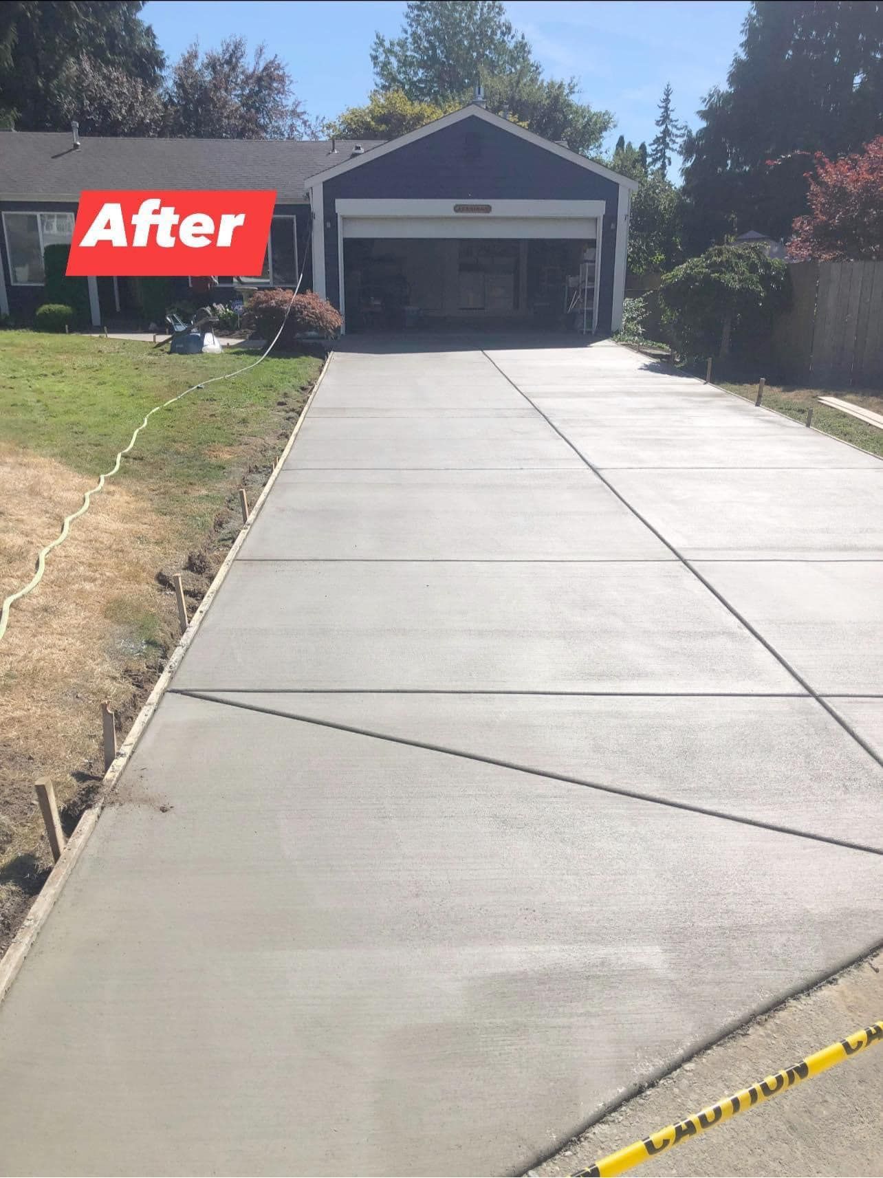 Newly poured concrete driveway in front of a blue house with a garage,