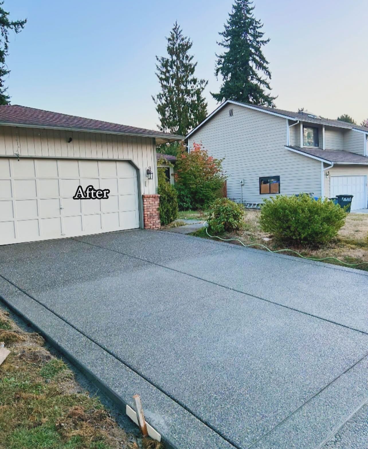 Newly paved concrete driveway in front of a garage and a two-story house.
