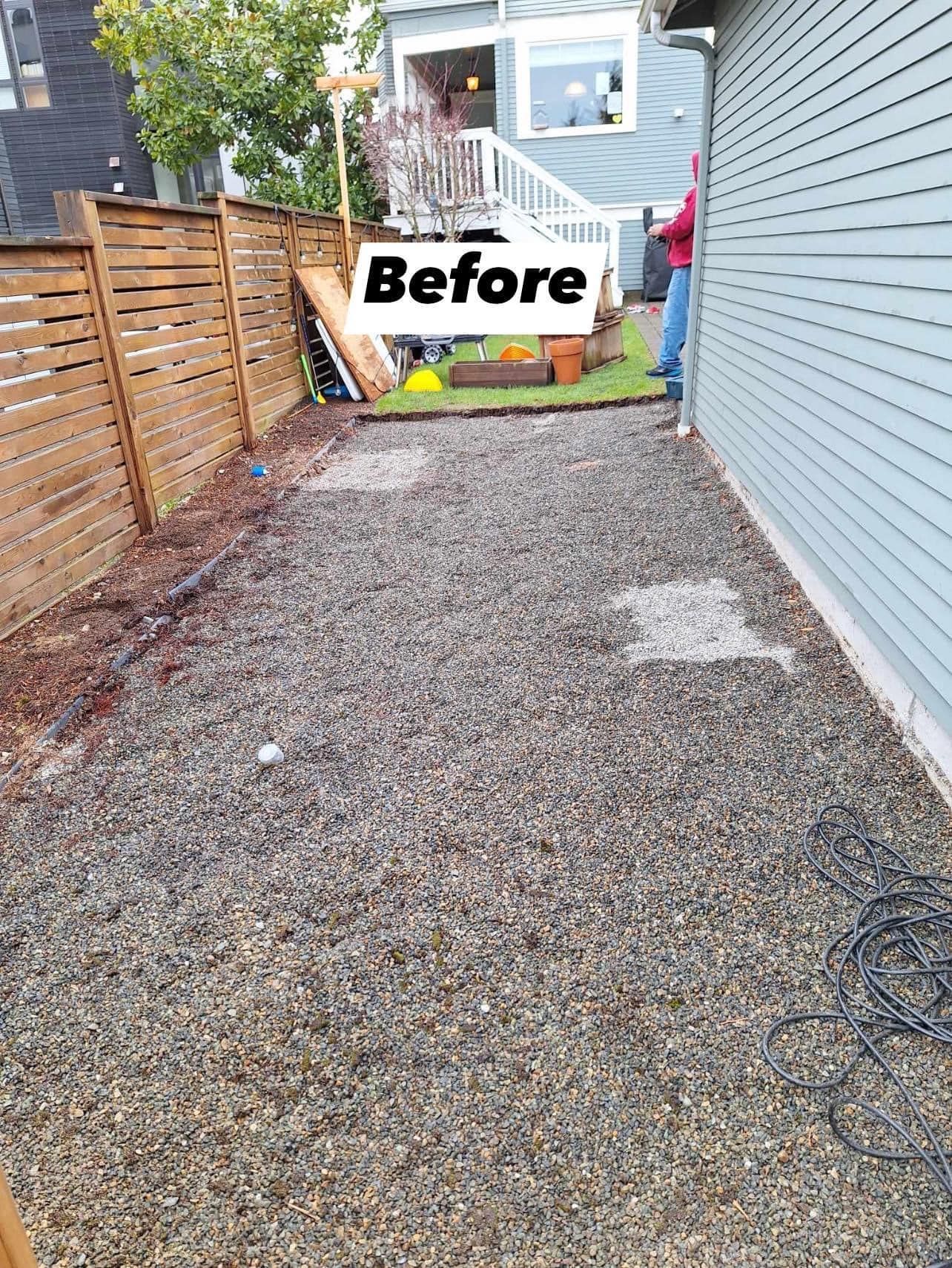 Gravel backyard before renovation next to a blue house and wooden fence.
