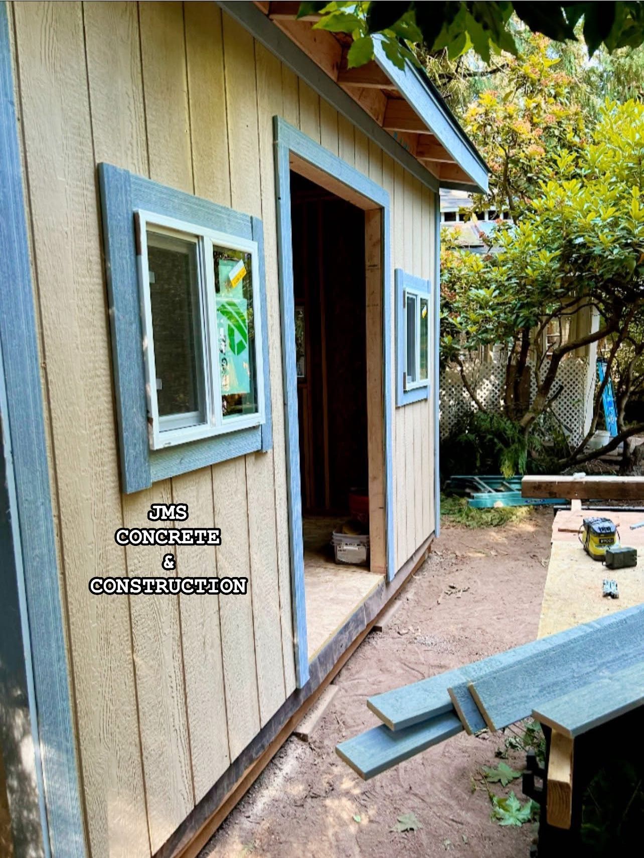 A partially built shed with blue trim and a yellow exterior; open doorway, window.