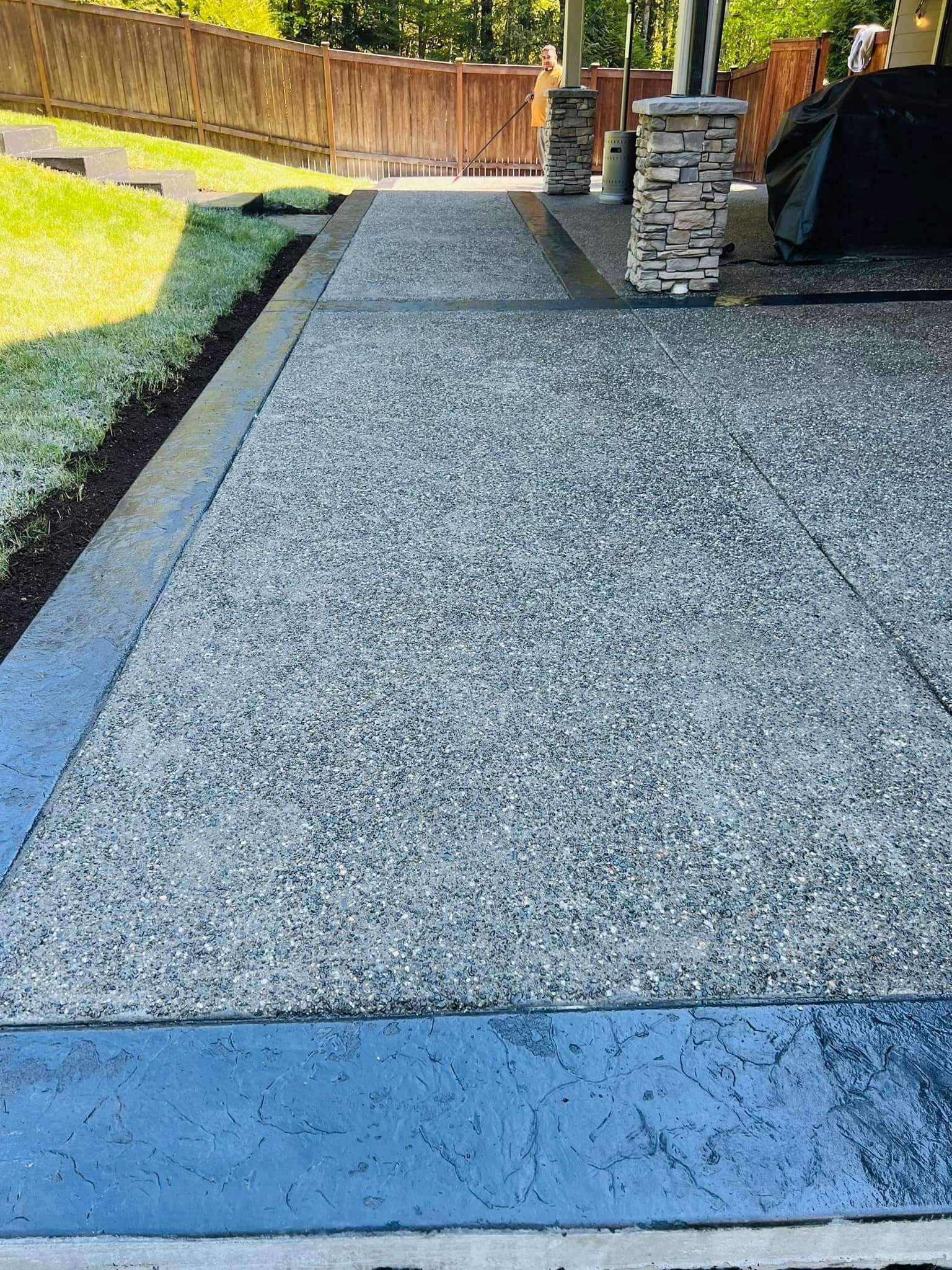 Concrete patio with stone pillars, bordered by a dark gray trim.