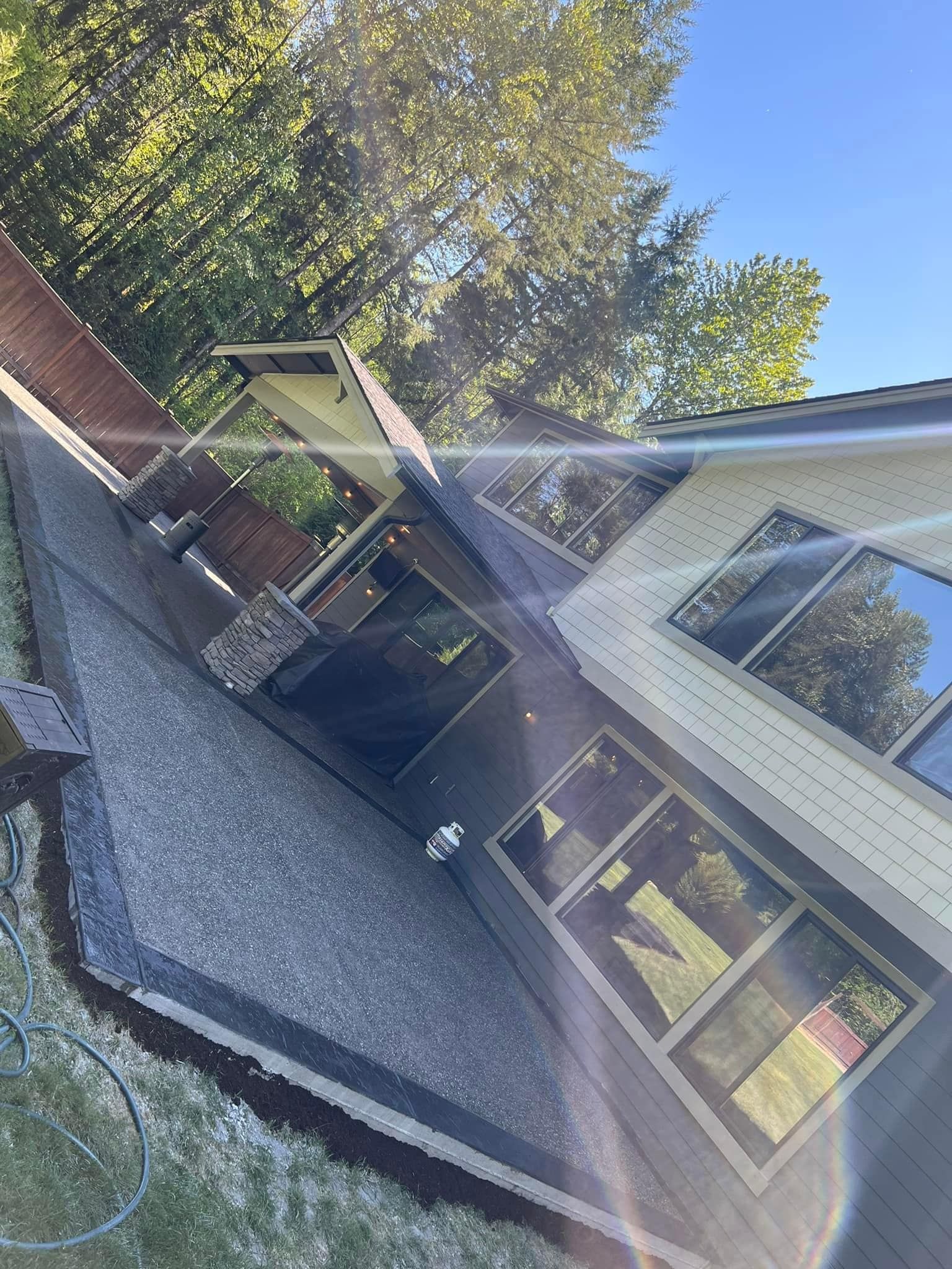 Angled view of house with gray roof, windows, and surrounding greenery.