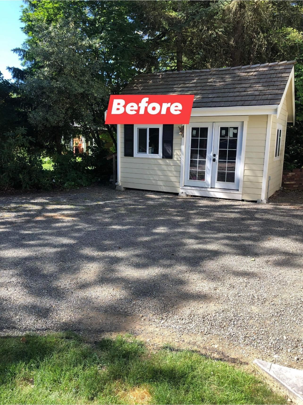 Small yellow shed with black shutters and double doors, gravel driveway, 
