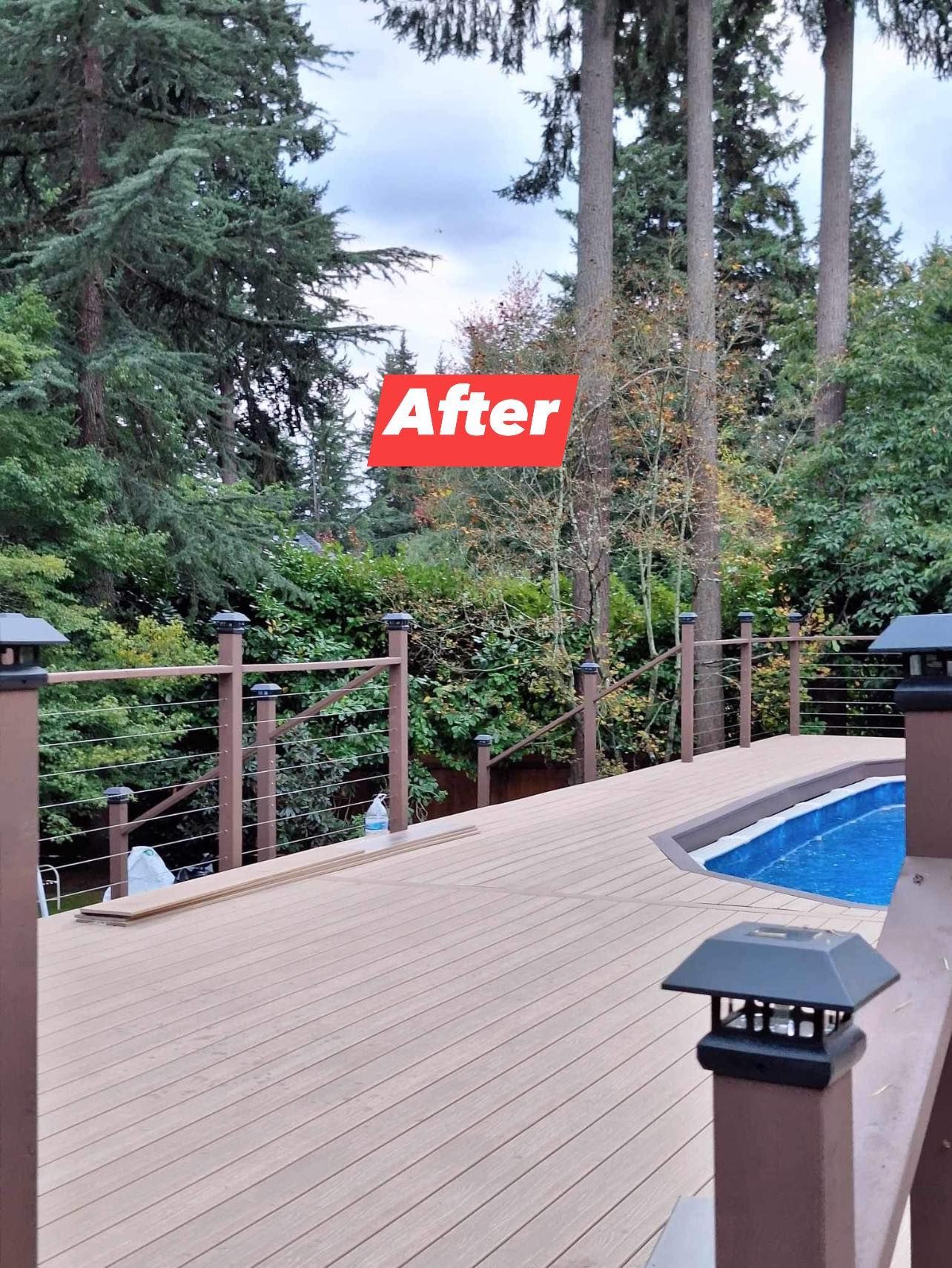 Deck with brown railings and composite decking surrounds a pool, surrounded by trees.