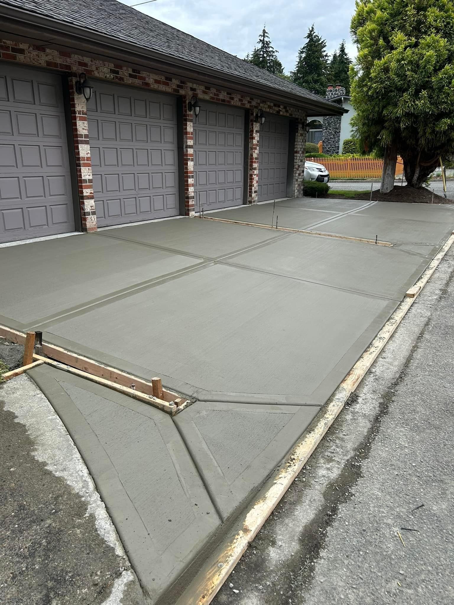 Freshly poured concrete driveway in front of a three-car garage.