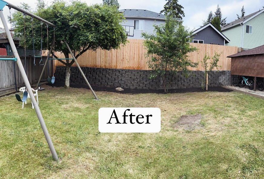 Backyard with a swing set, new retaining wall, and fresh mulch.  