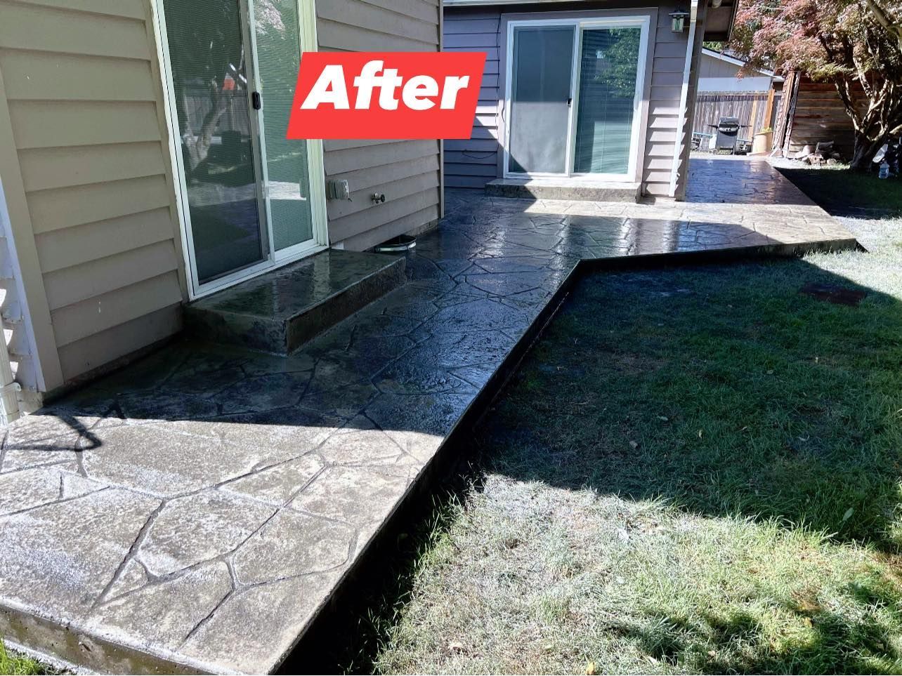 Stamped concrete patio, freshly sealed, next to a grassy lawn and a house with sliding glass doors.