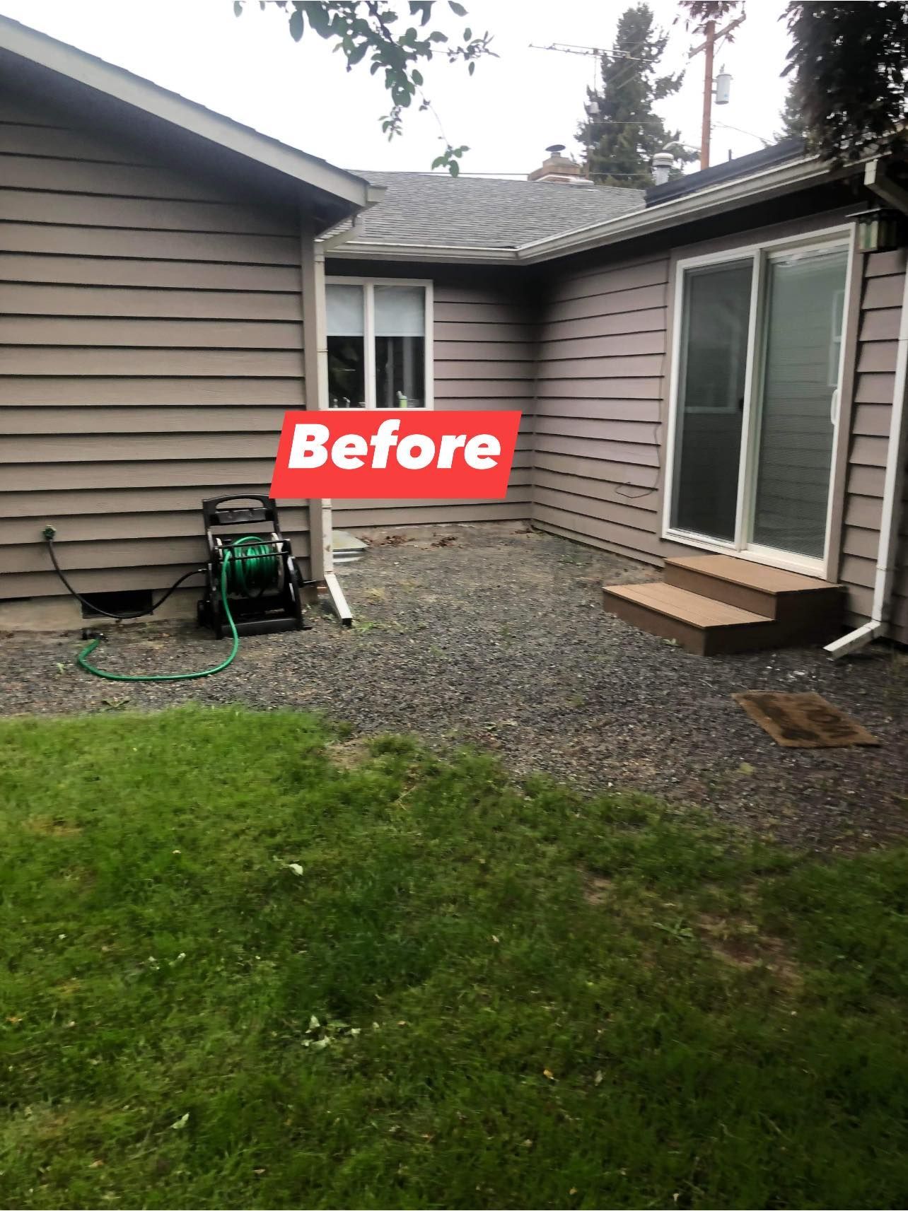 Backyard before renovation: Gravel patio area between two buildings, with a hose and sliding door.