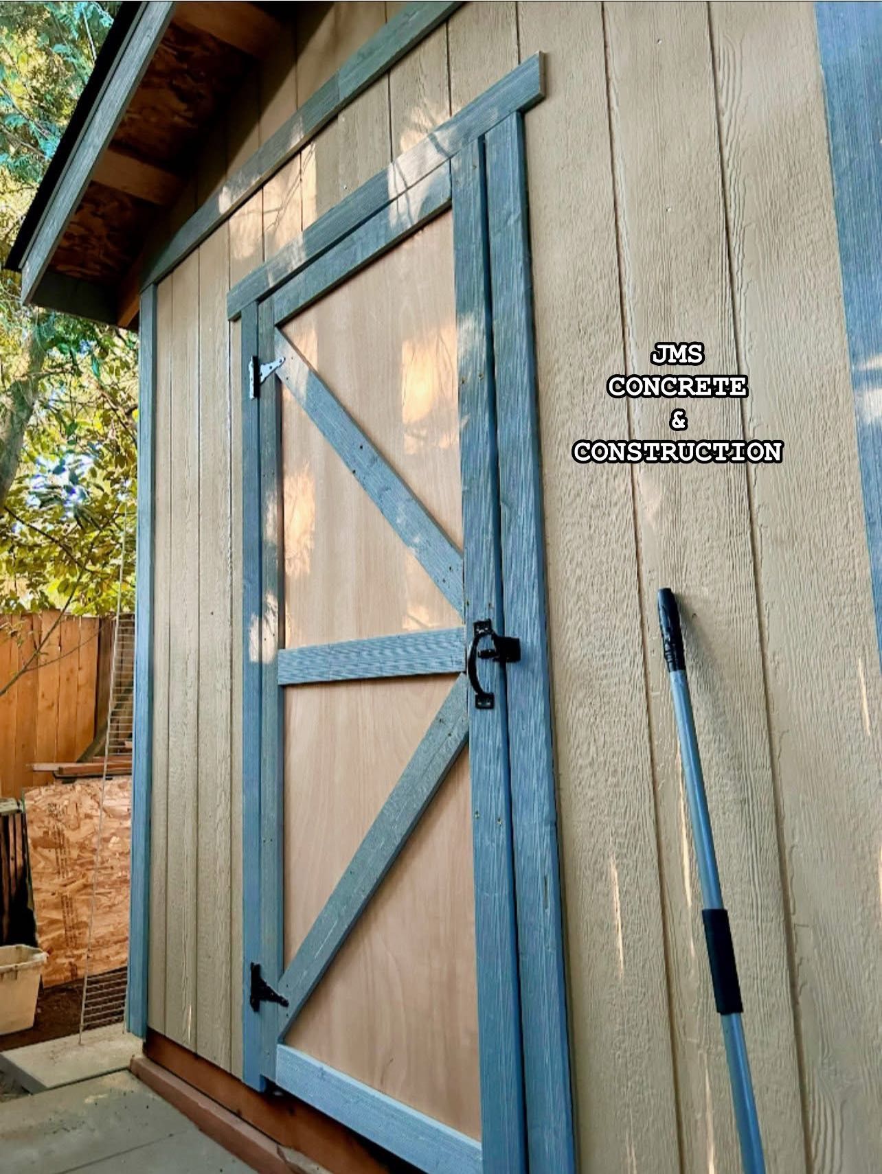 Wooden shed door with gray trim and diagonal bracing, exterior view.