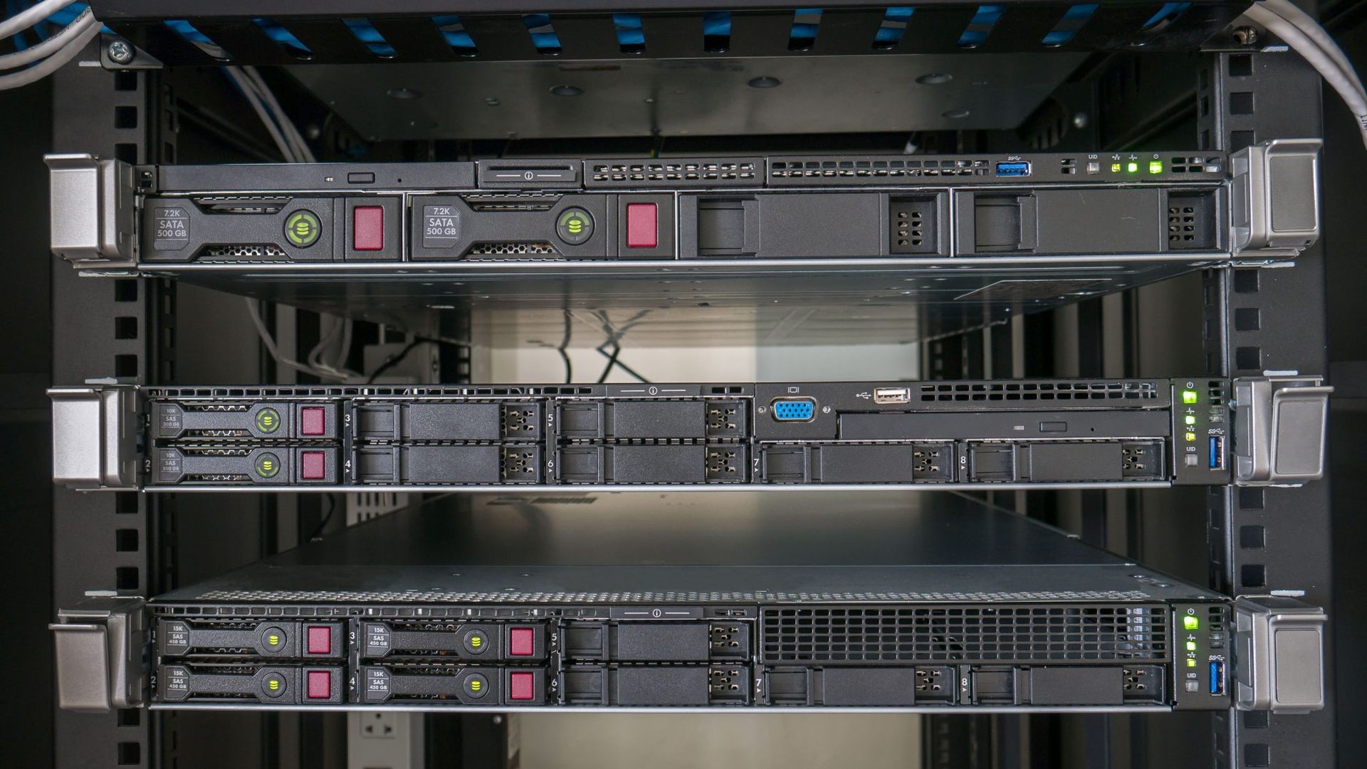Three stacked server racks with cables and indicator lights in a data center rack cabinet