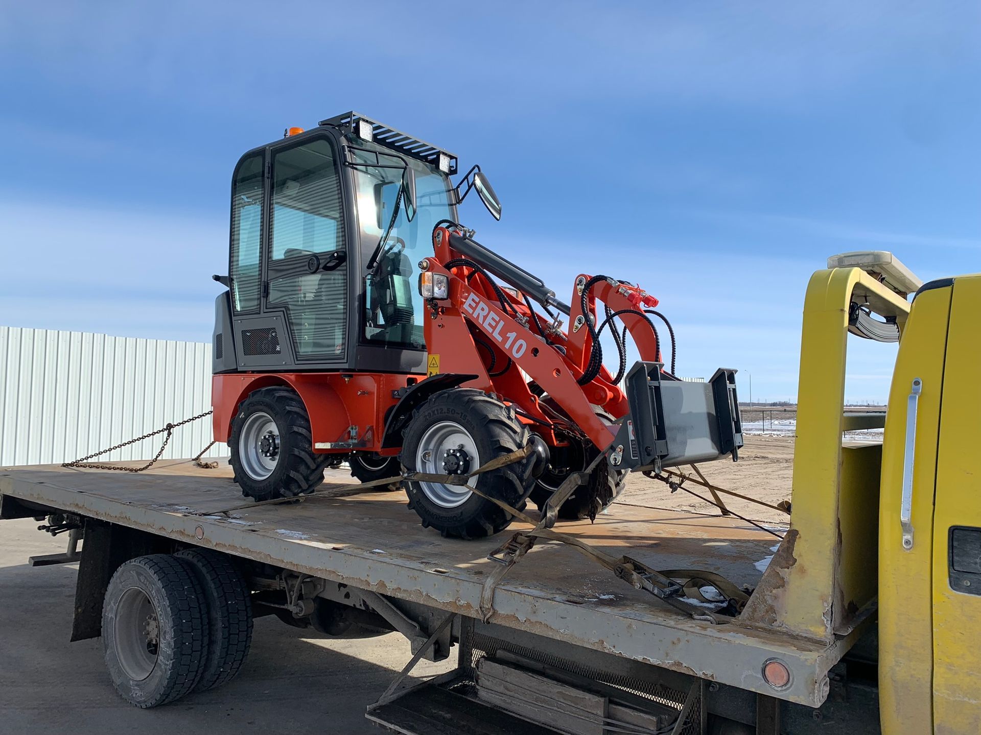 A forklift being towed by a flatbed tow truck in Winnipeg