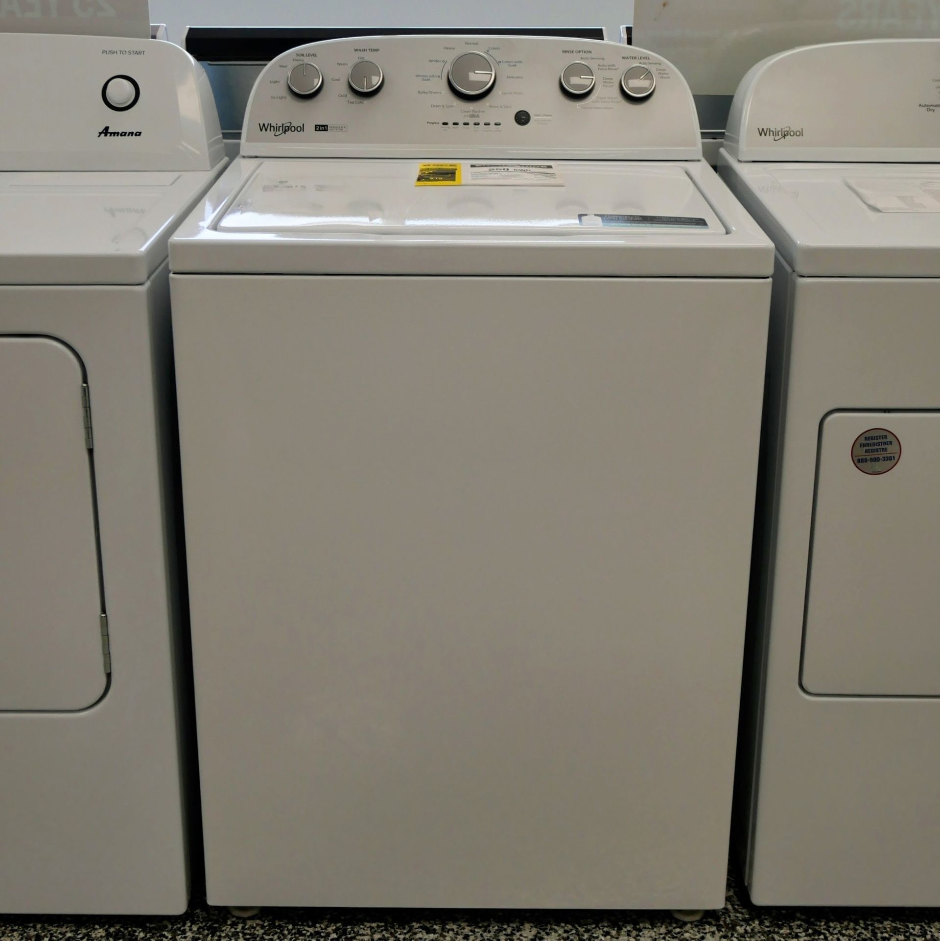 Three white, top-loading washing machines and dryers side by side in a store.