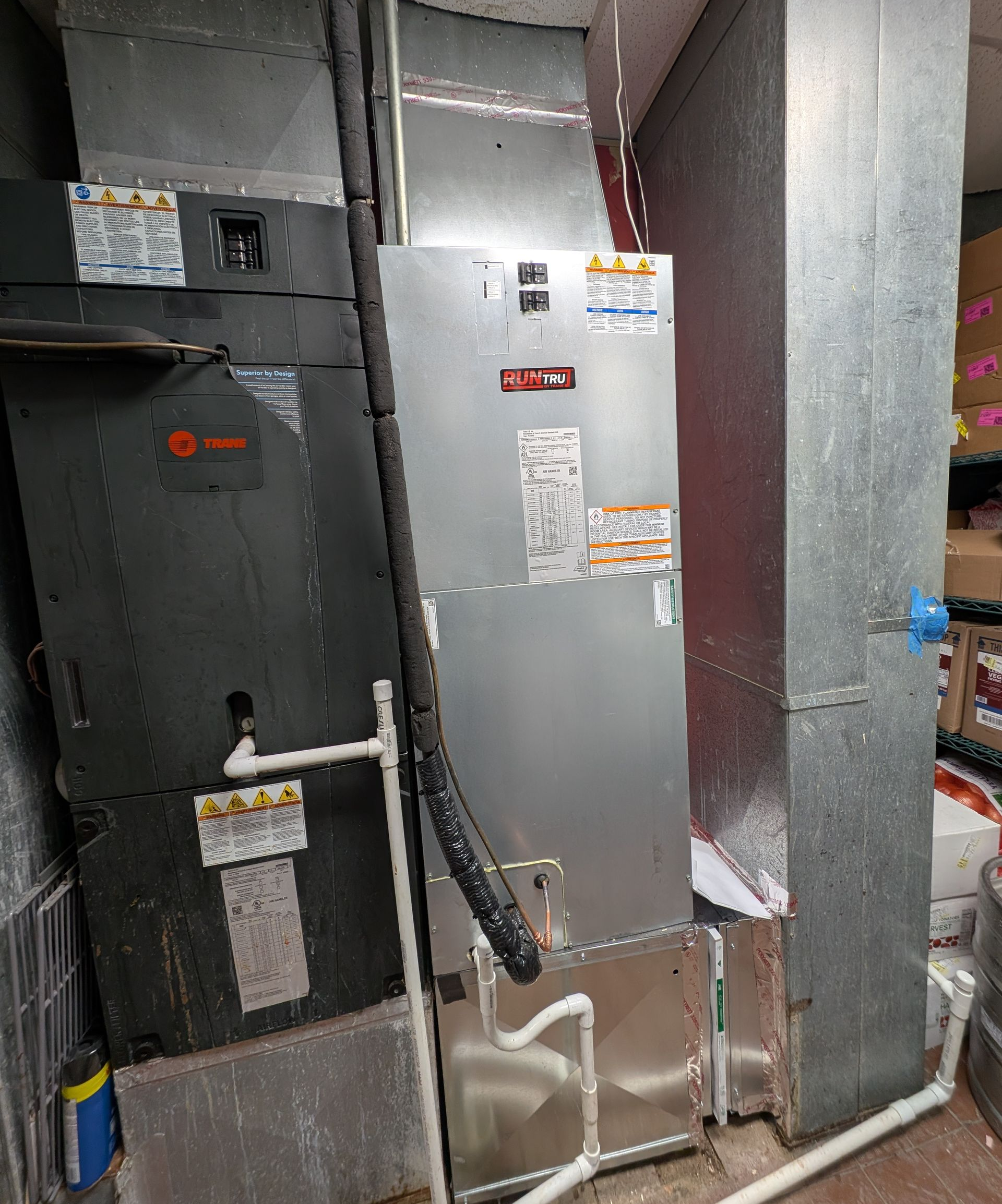 Interior of utility room with pipes, ducts, and machinery, white and silver tones.