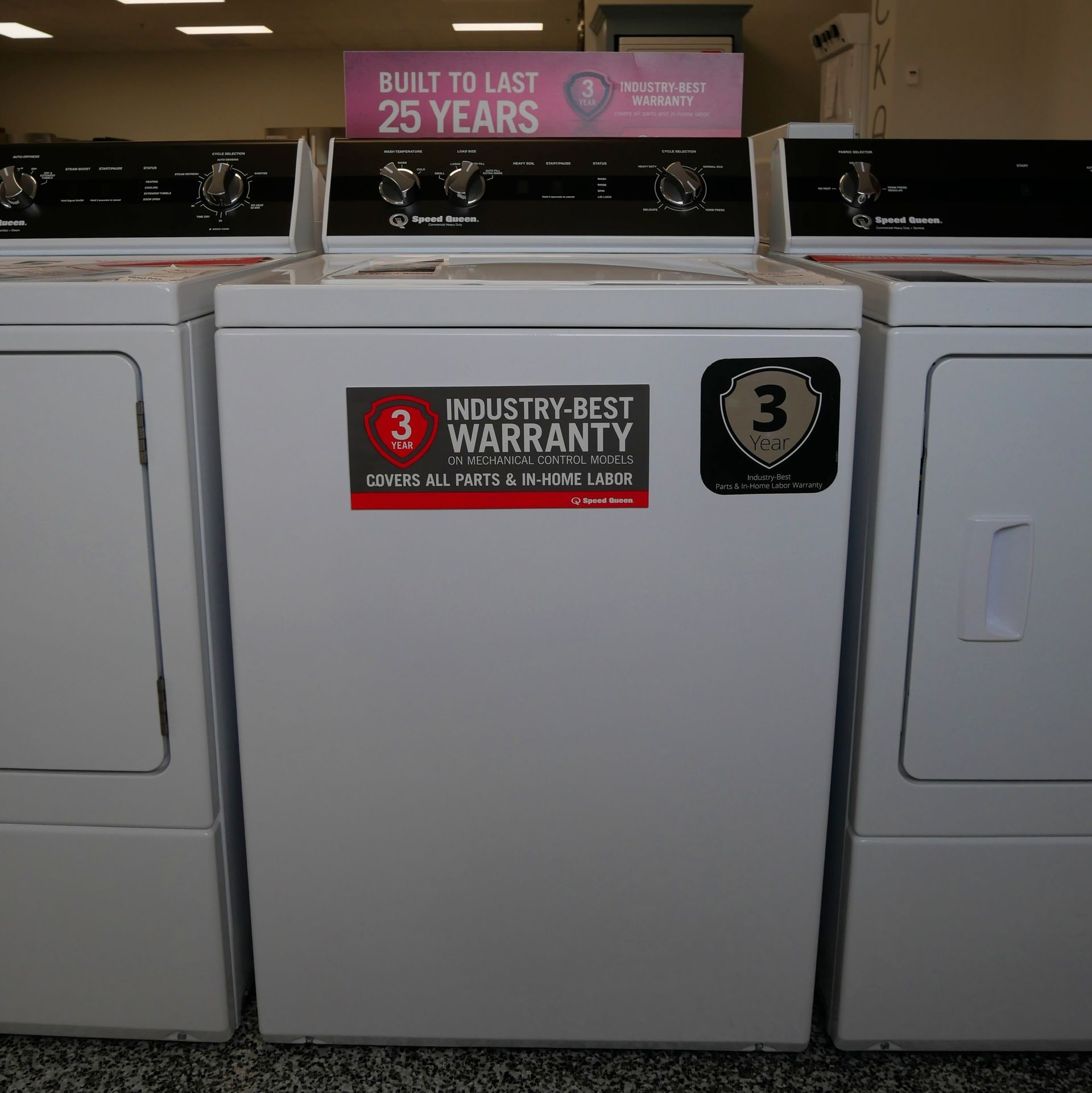 Three white washing machines with control panels, in a store setting. One has an 
