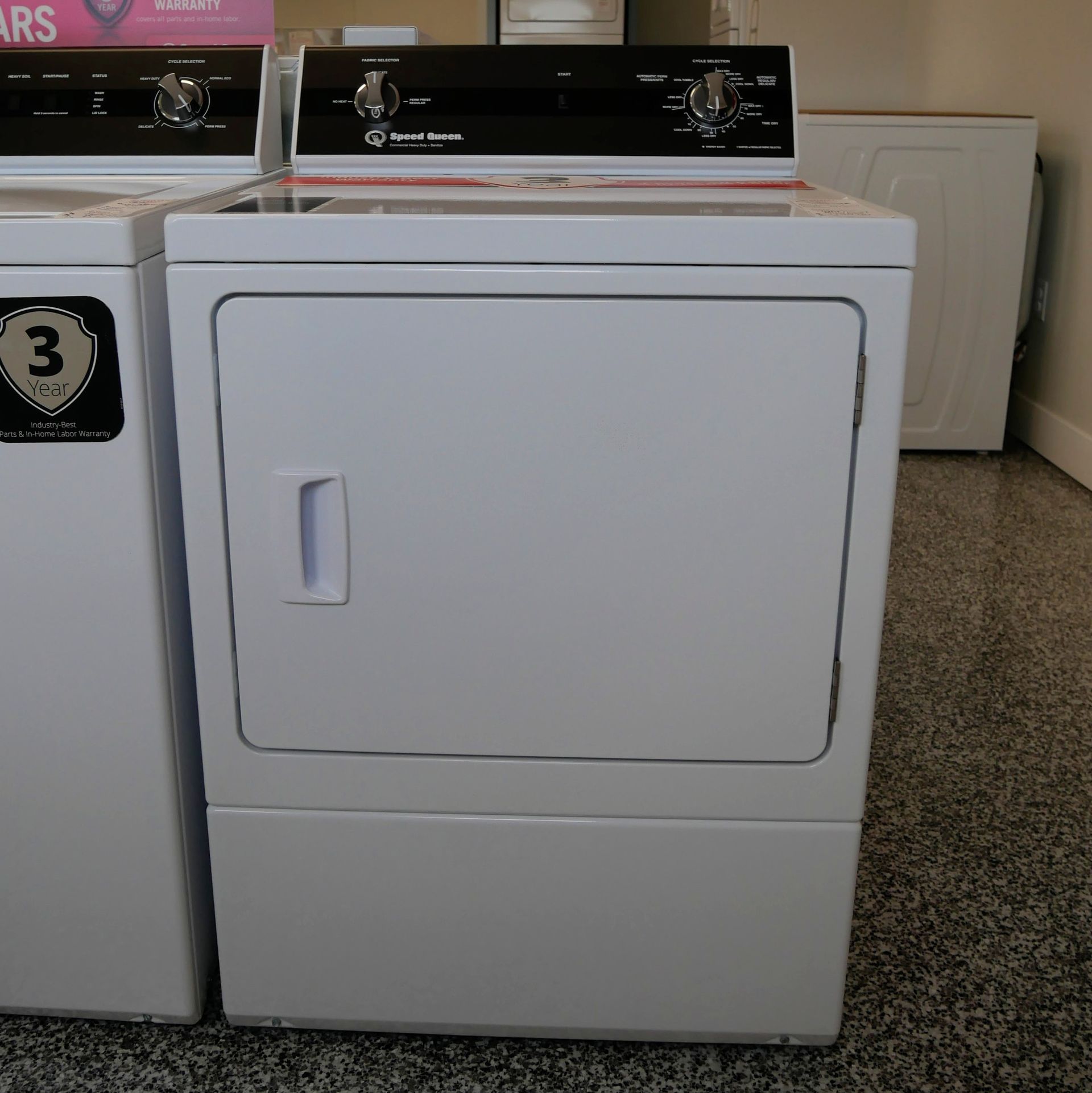 White electric clothes dryer with black top controls in a store.