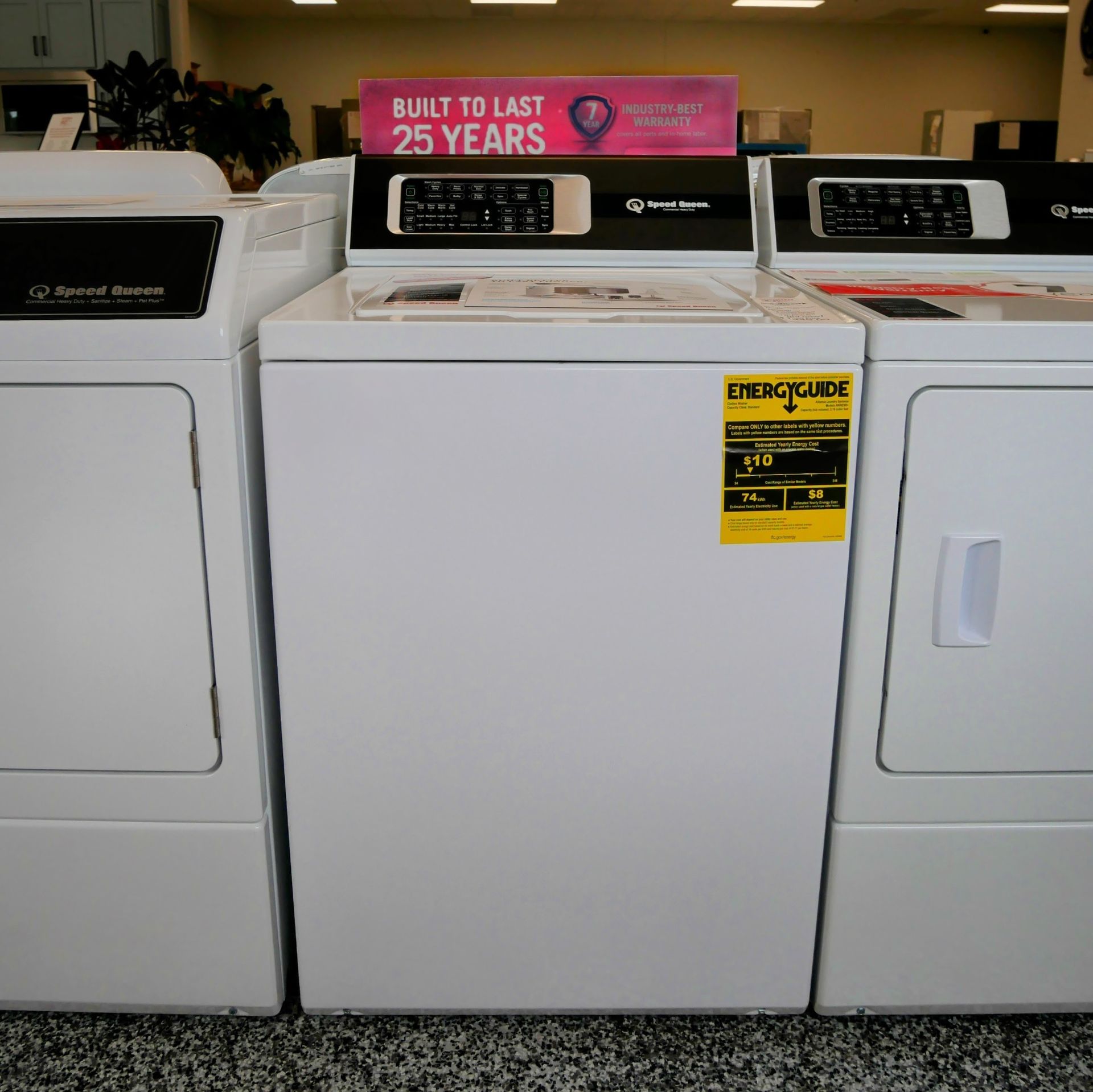 Three white washing machines and dryers side by side in a store, energy guide sticker on one.