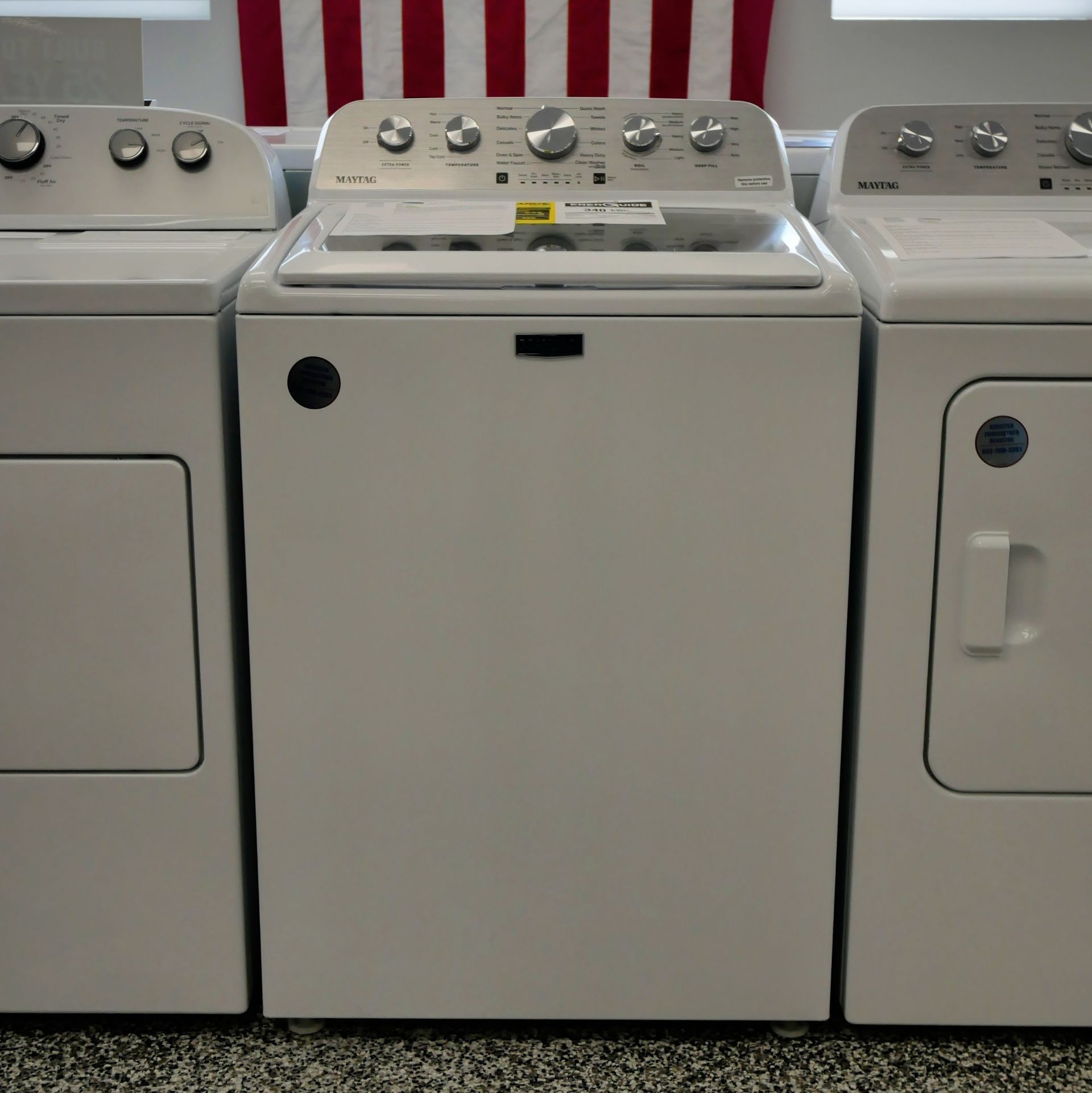 White washing machine and dryer set with an American flag in the background.