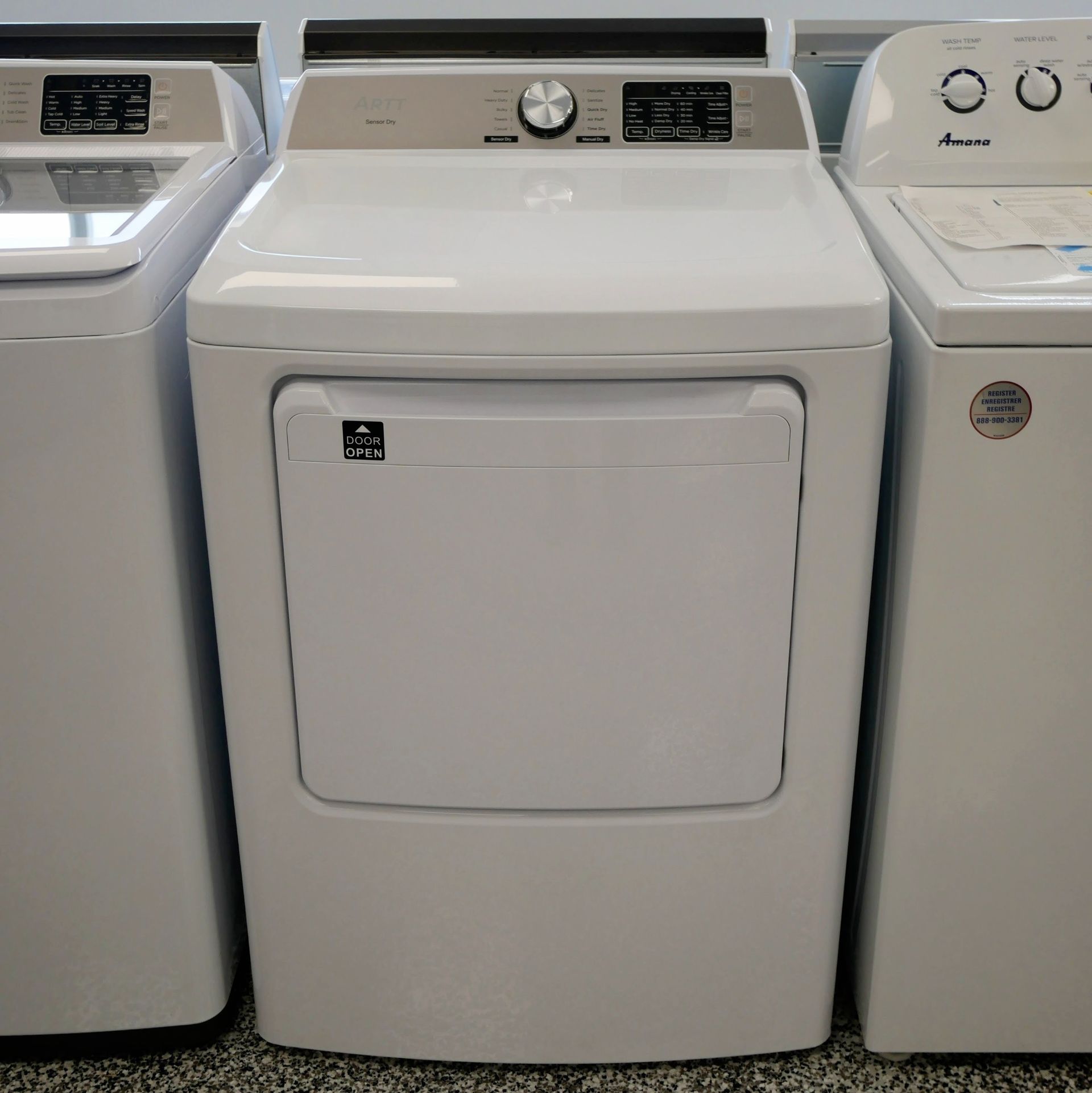 White dryer machine in a showroom, flanked by other appliances.