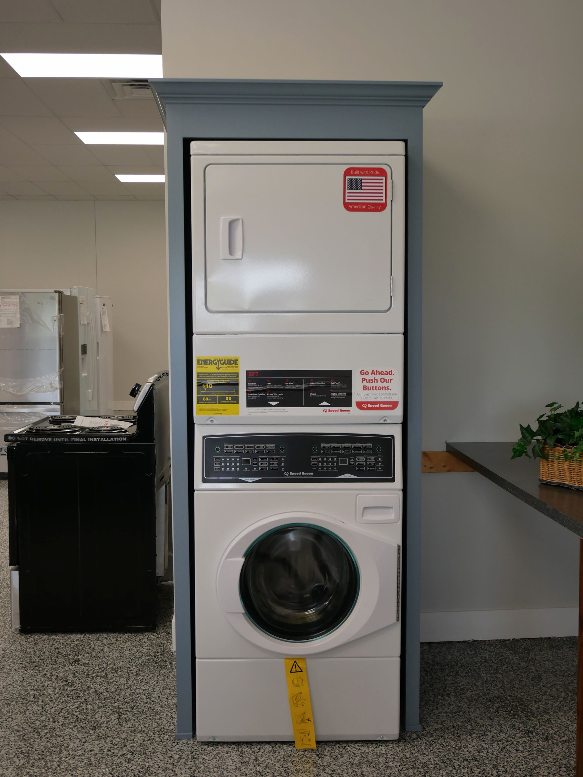 Stacked white washer and dryer unit within a blue-painted recessed frame.