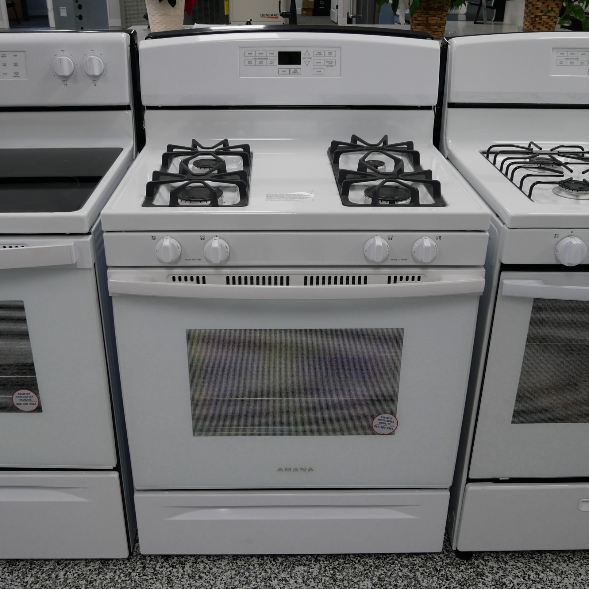 White gas range appliance with four burners and oven, in a store setting.