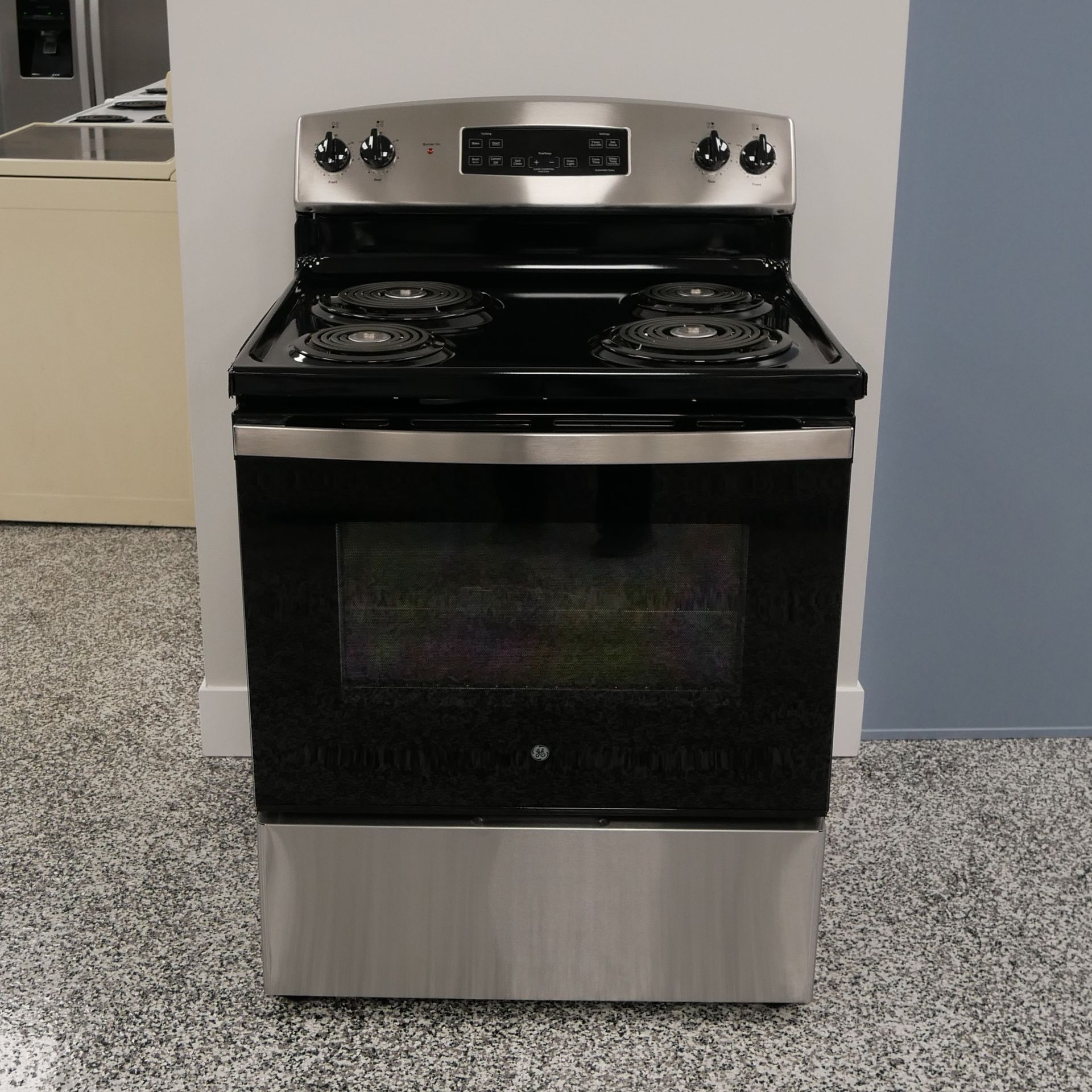 Electric range with black cooktop, stainless steel body, and glass oven door.