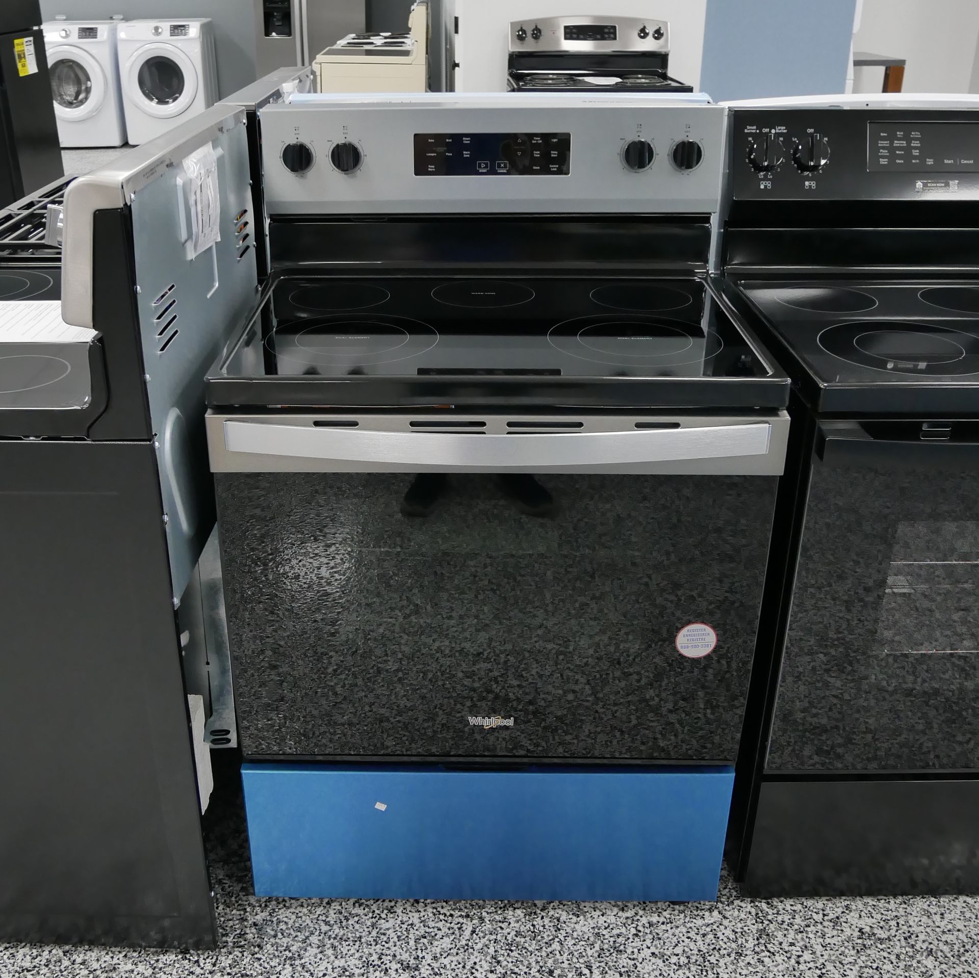 Electric Whirlpool range, stainless steel with black cooktop and oven, blue base support.