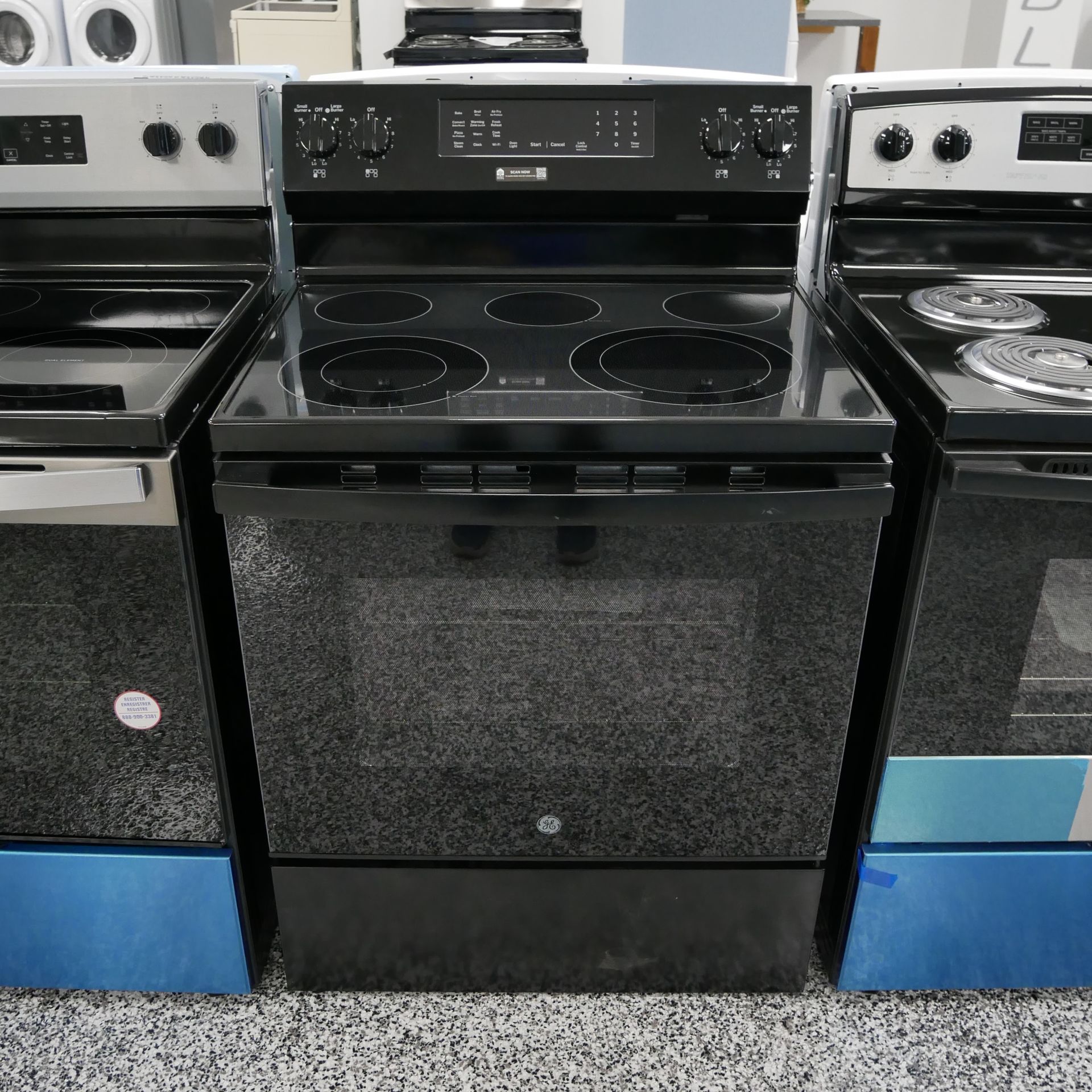 Three black electric stoves lined up. The center one is the main focus.