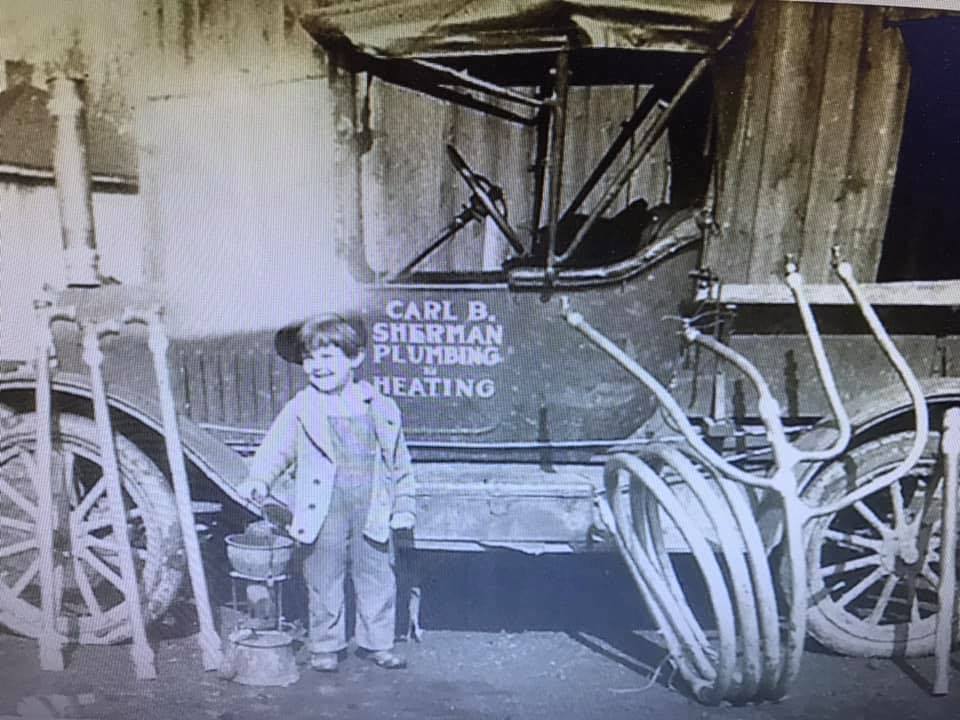 Young child stands by a vintage plumbing truck.