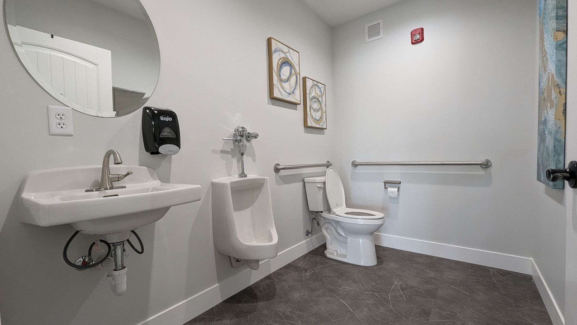 A bathroom with a toilet , urinal , sink and mirror.