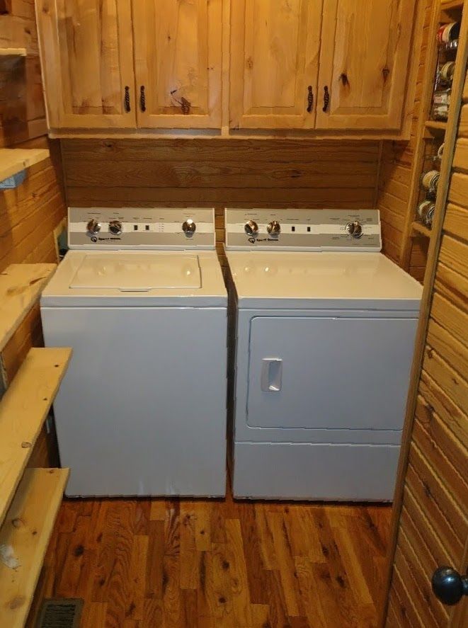 Laundry room with a white washing machine and dryer, wooden cabinets and paneling.