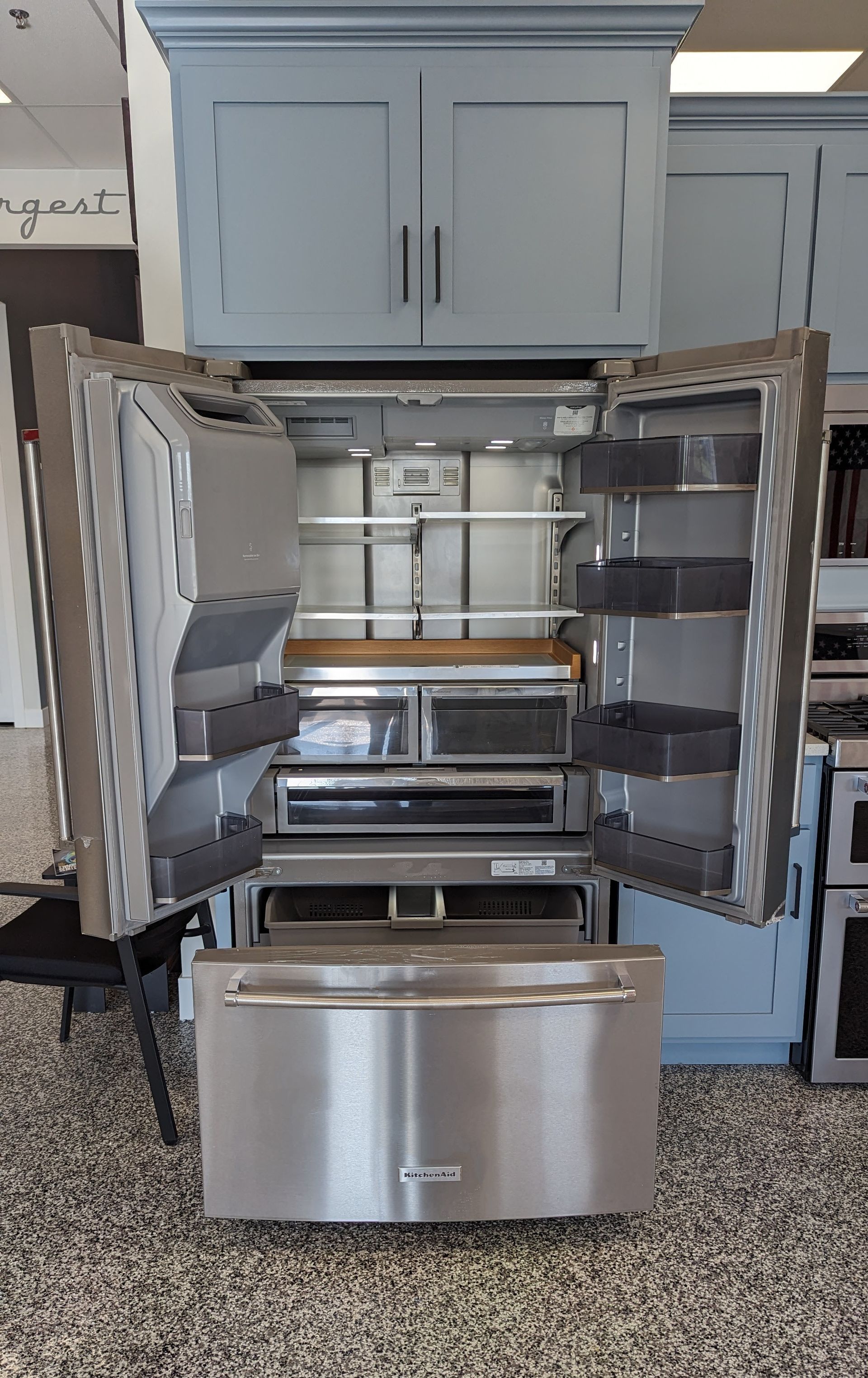 Stainless steel refrigerator with open doors in a showroom.
