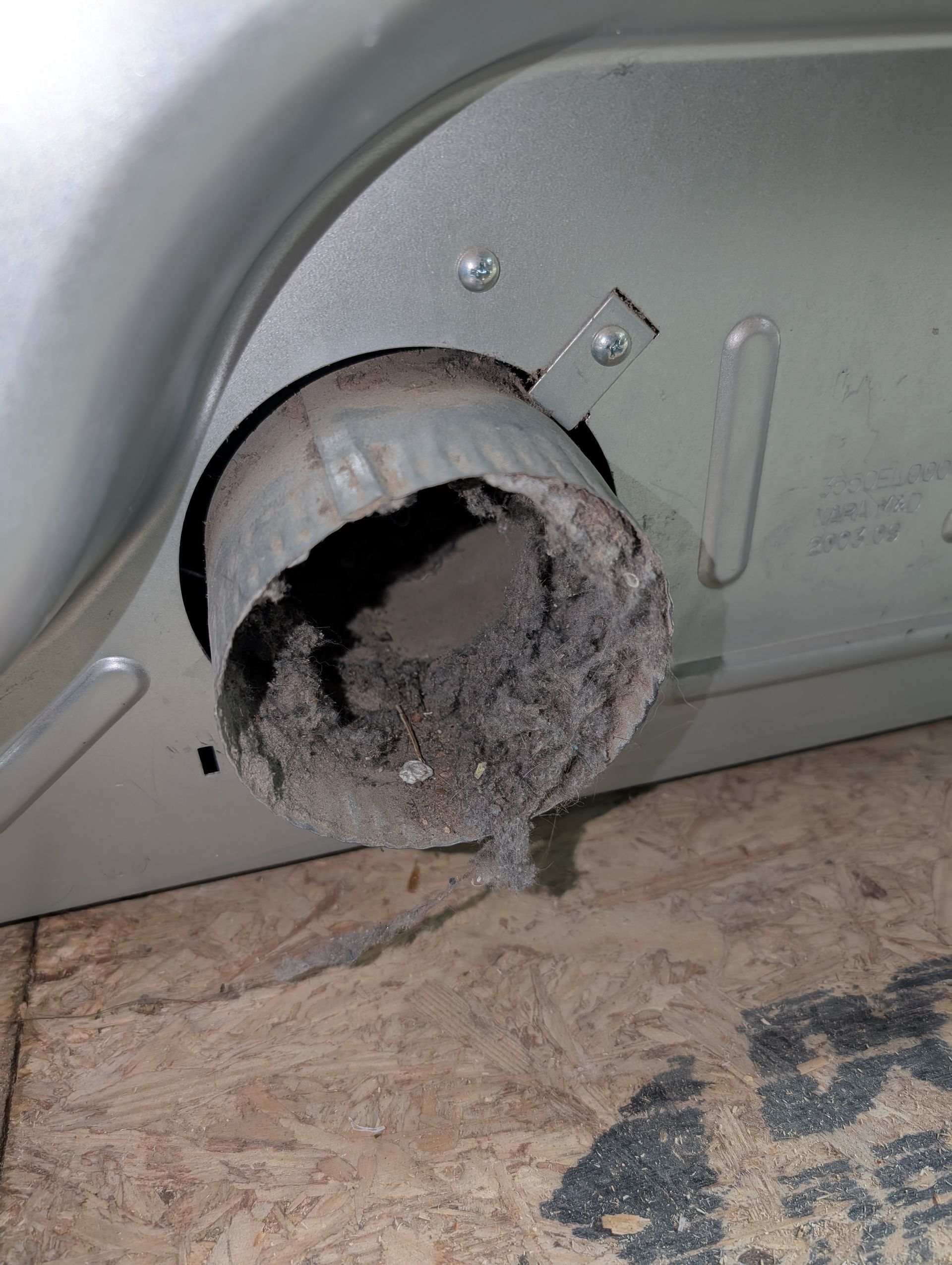 A close up of a dryer with a hole in it filled with dust.