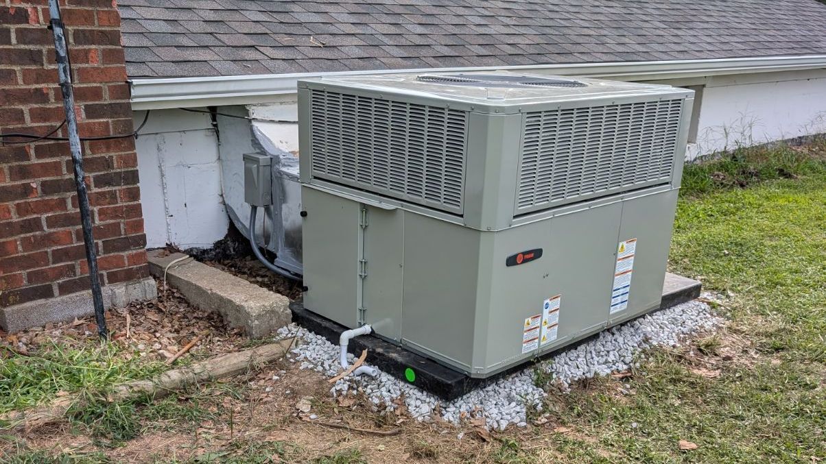 A large air conditioner is sitting on the side of a brick building.