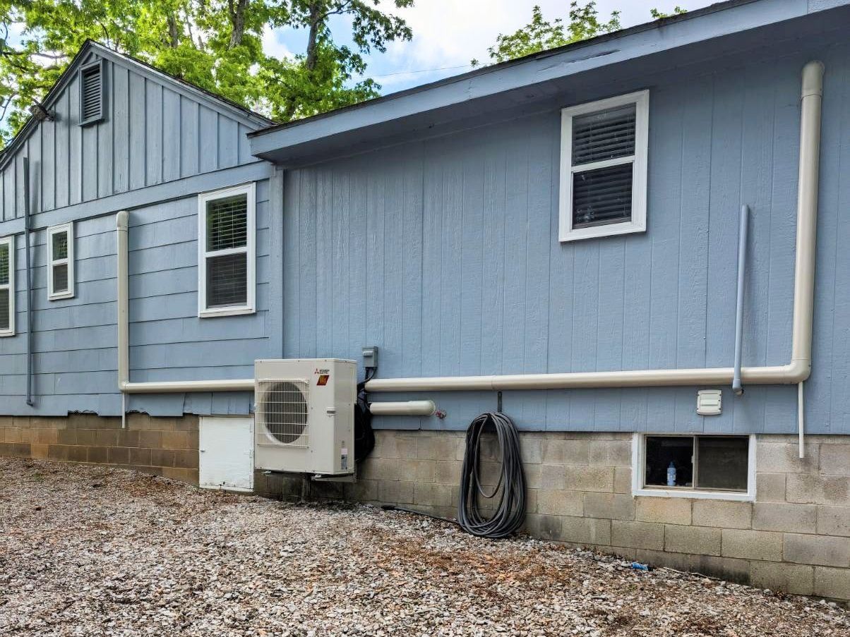 A blue house with a white air conditioner on the side of it.