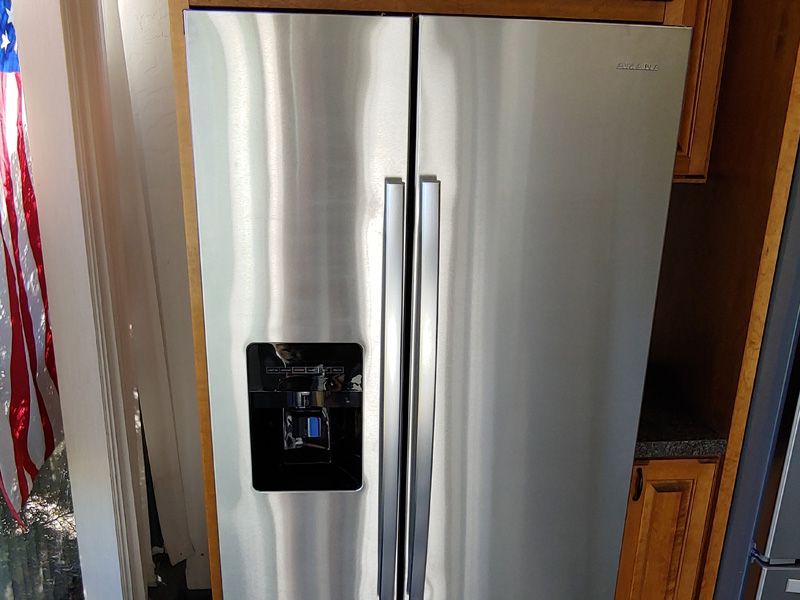 Stainless steel side-by-side refrigerator in a kitchen, with water and ice dispenser.