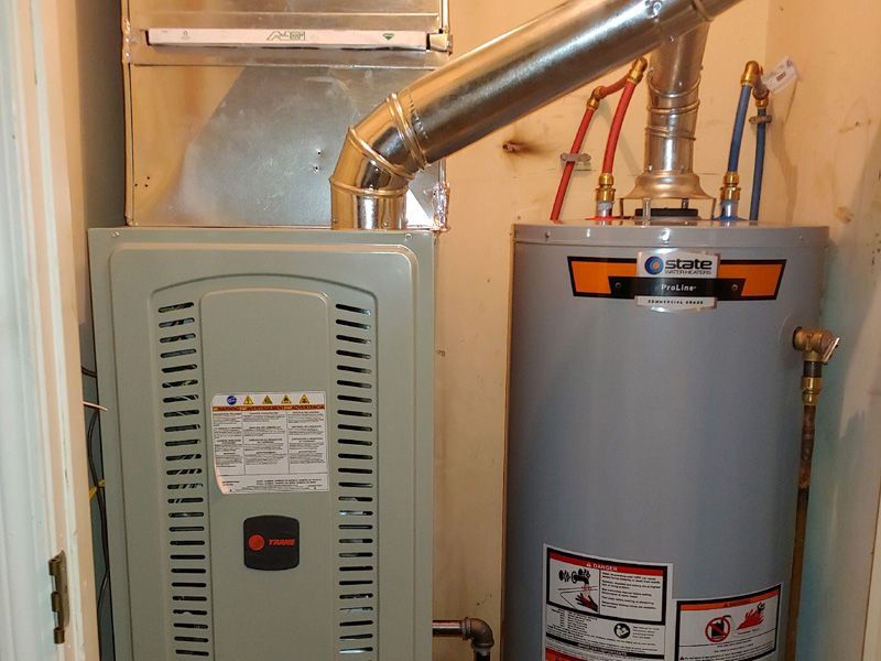 Furnace and water heater in a utility closet with vent pipes, blue and red pipes.