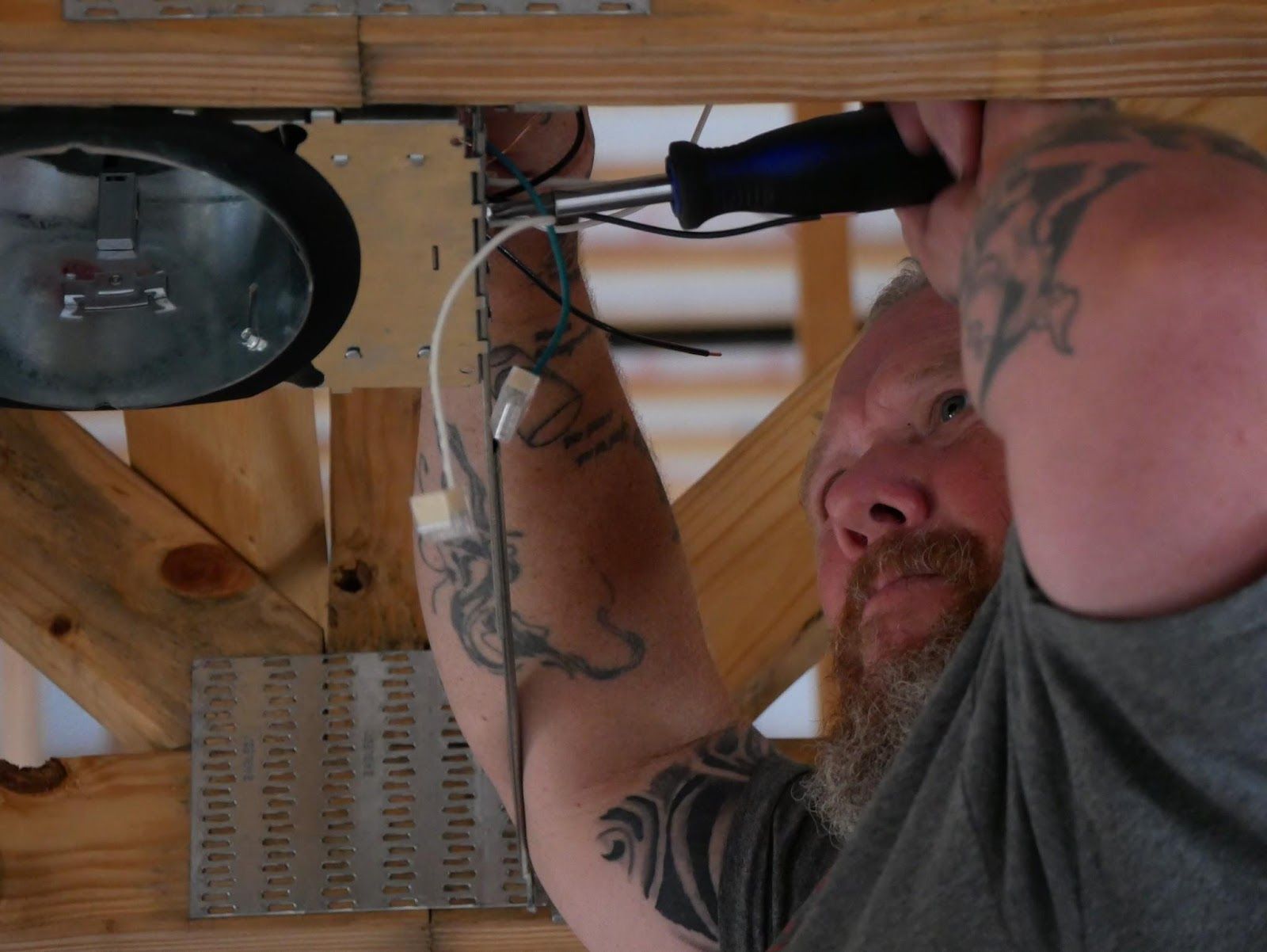 A man with a tattoo on his arm is working on a light