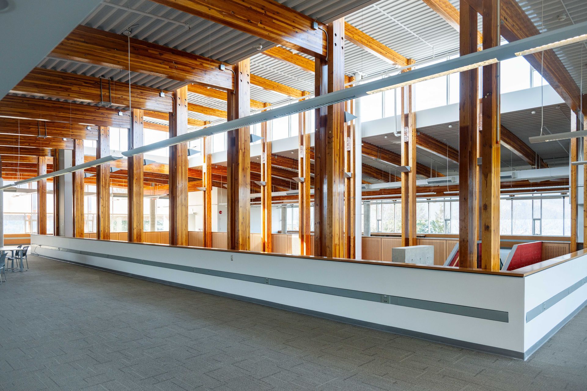 Interior of a modern unfinished building with exposed wooden beams and a low white partition wall.