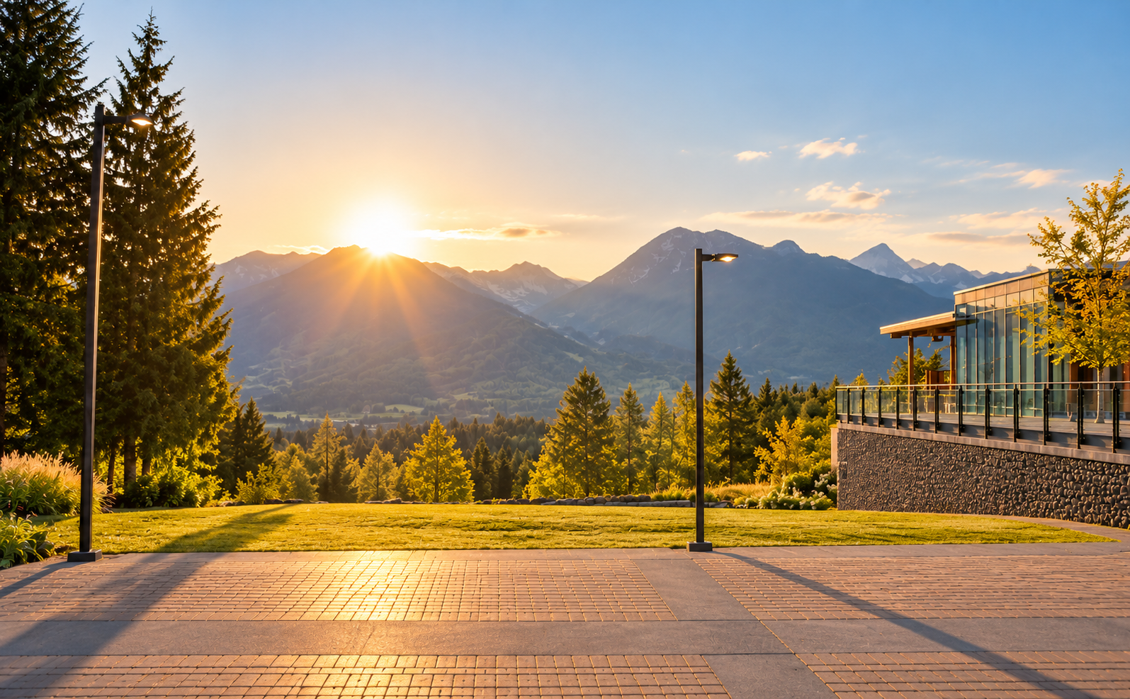 Sunrise over mountain valley with paved terrace, trees, and a stone railing