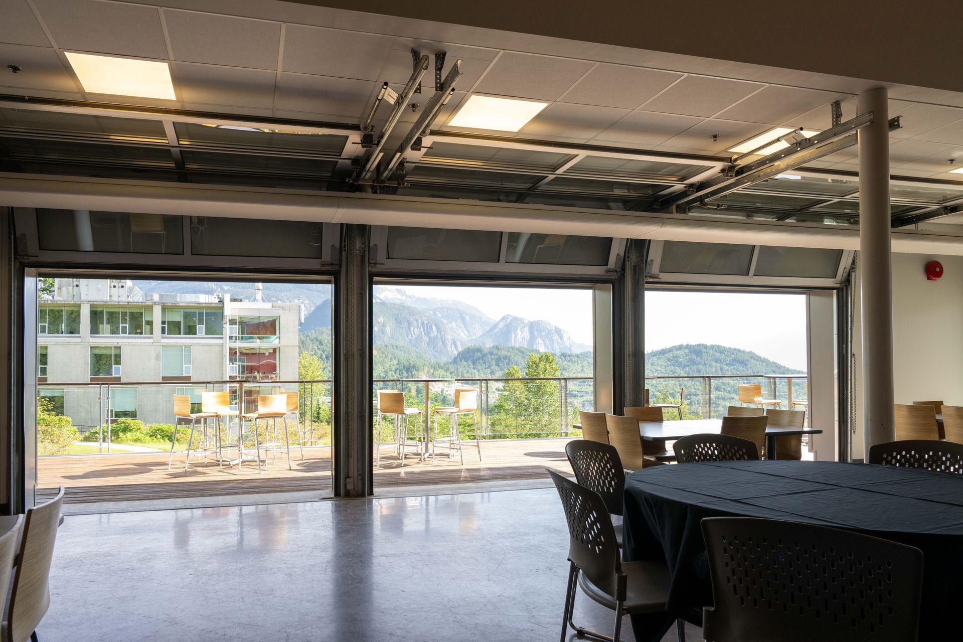 Empty modern room with large windows, tables, and mountain view outside