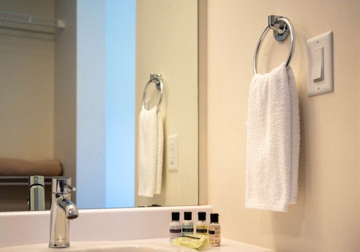 Bathroom sink with towel ring holding a white towel, reflected in the mirror.