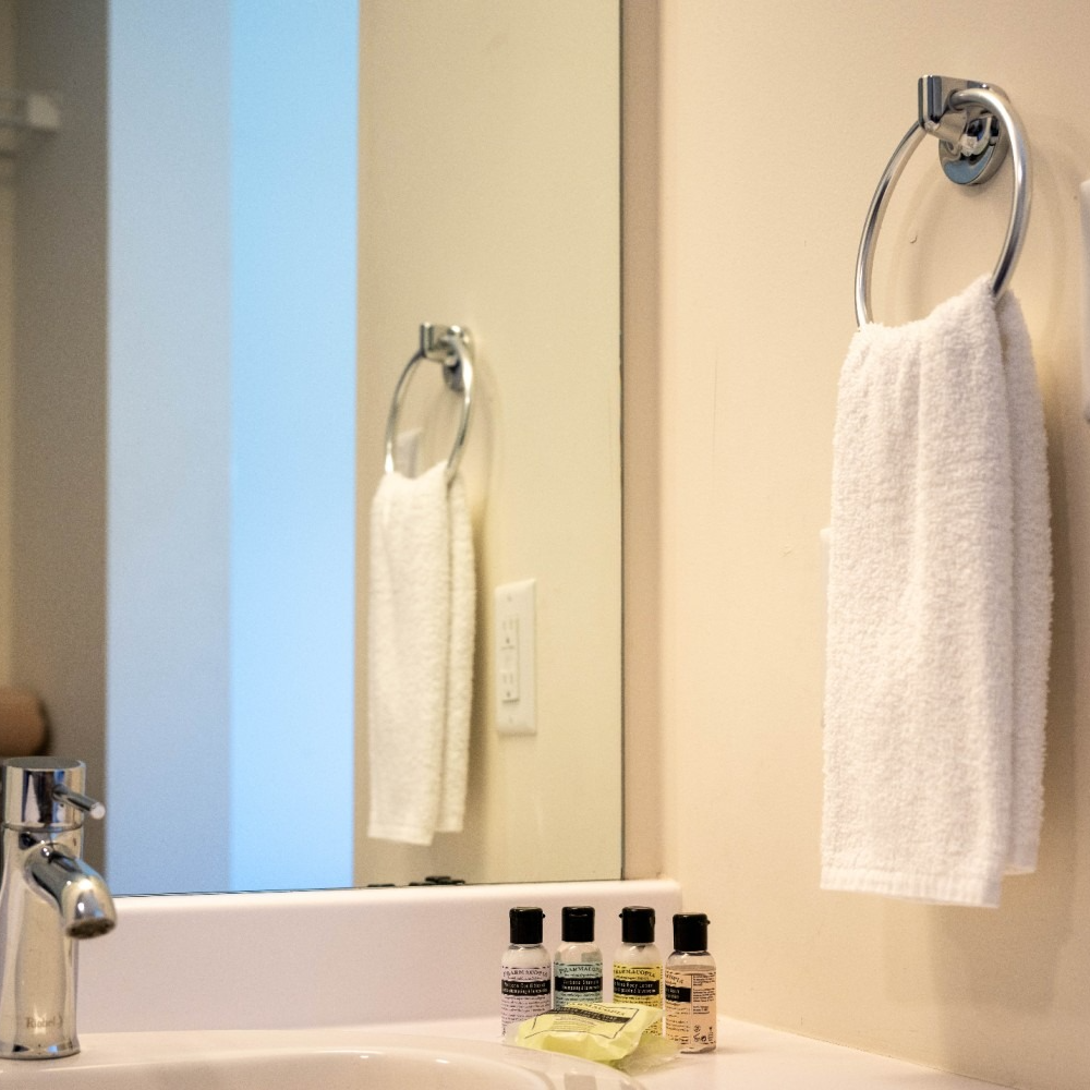 Bathroom sink with mirror reflecting a towel rack and white towel.