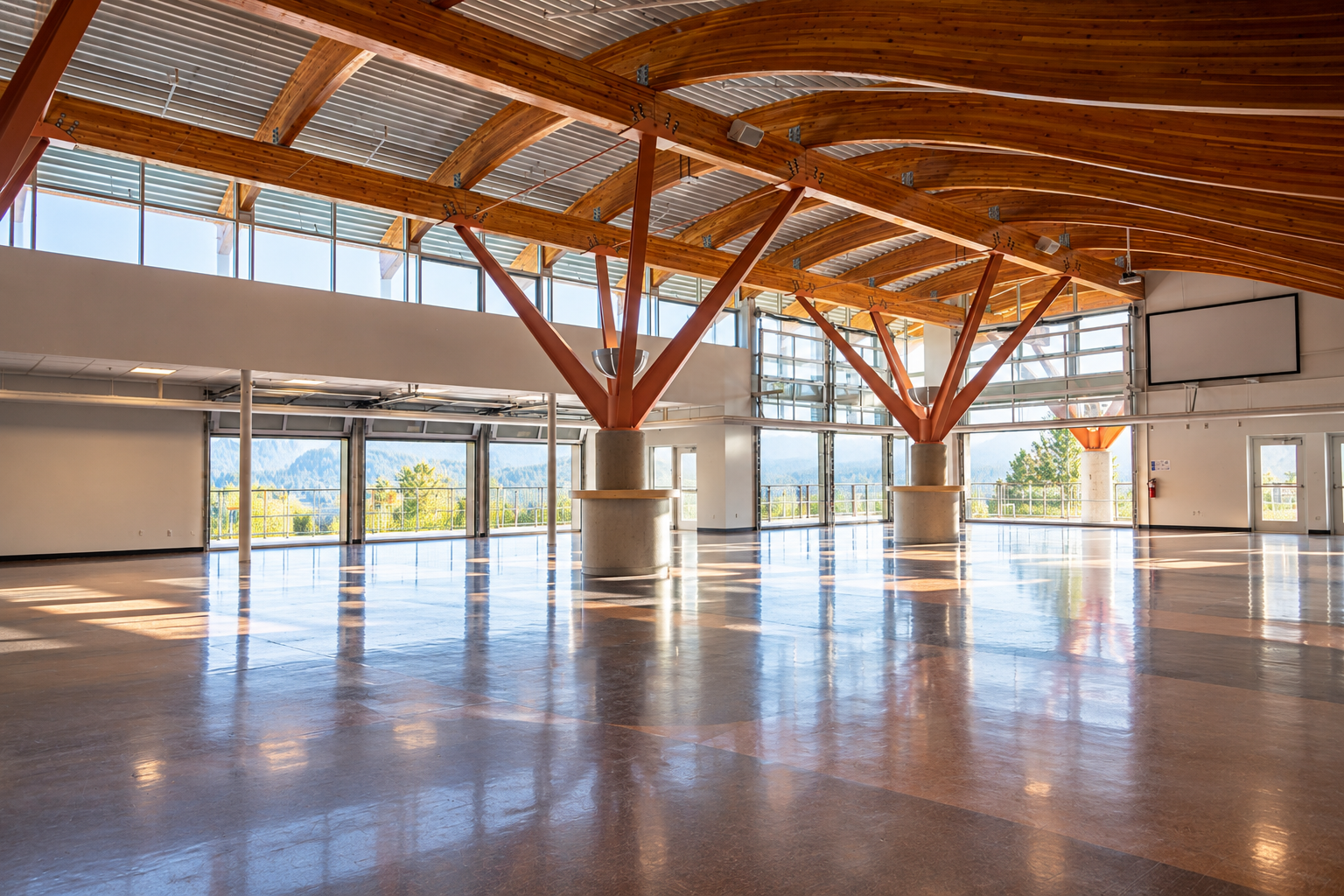 Empty indoor gymnasium with polished floor, wooden roof beams, and sunlight from large windows