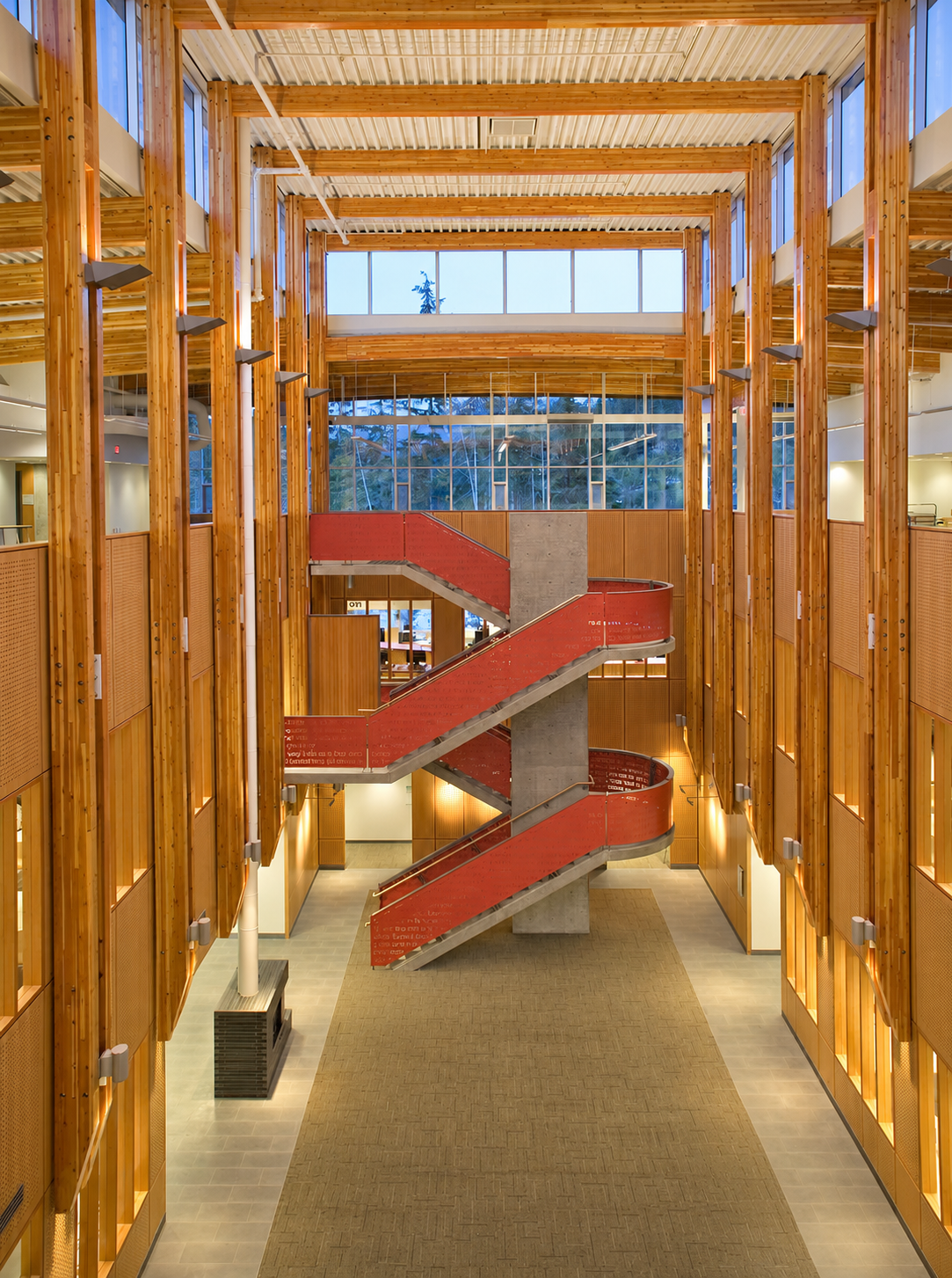 Modern wooden atrium with red staircases and a high ceiling
